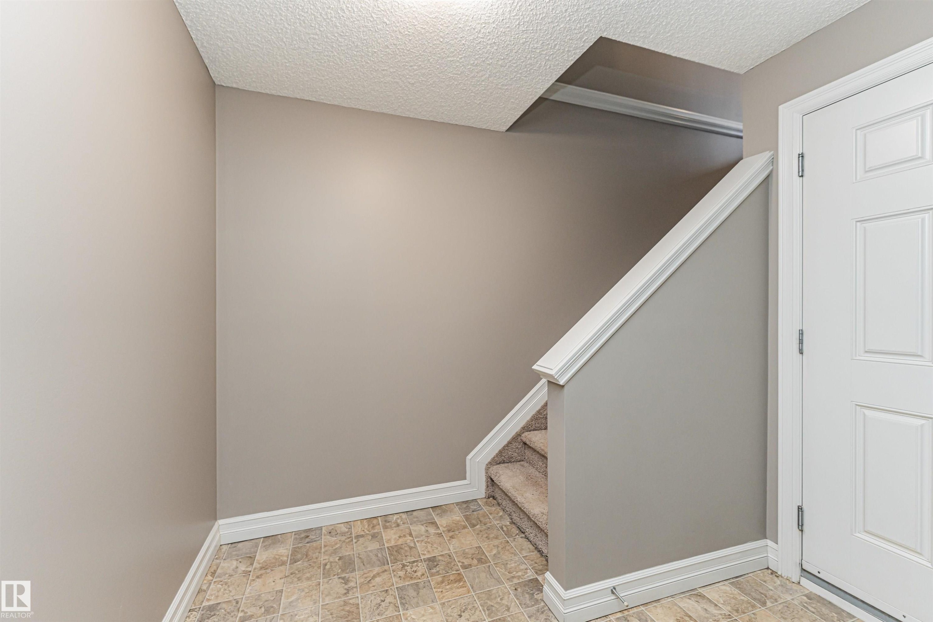 Entryway featuring a white paneled door, neutral wall color, and patterned floor tiles - #110 3625 144 Av Nw, Edmonton, AB - Indoor Photo Showing Other Room