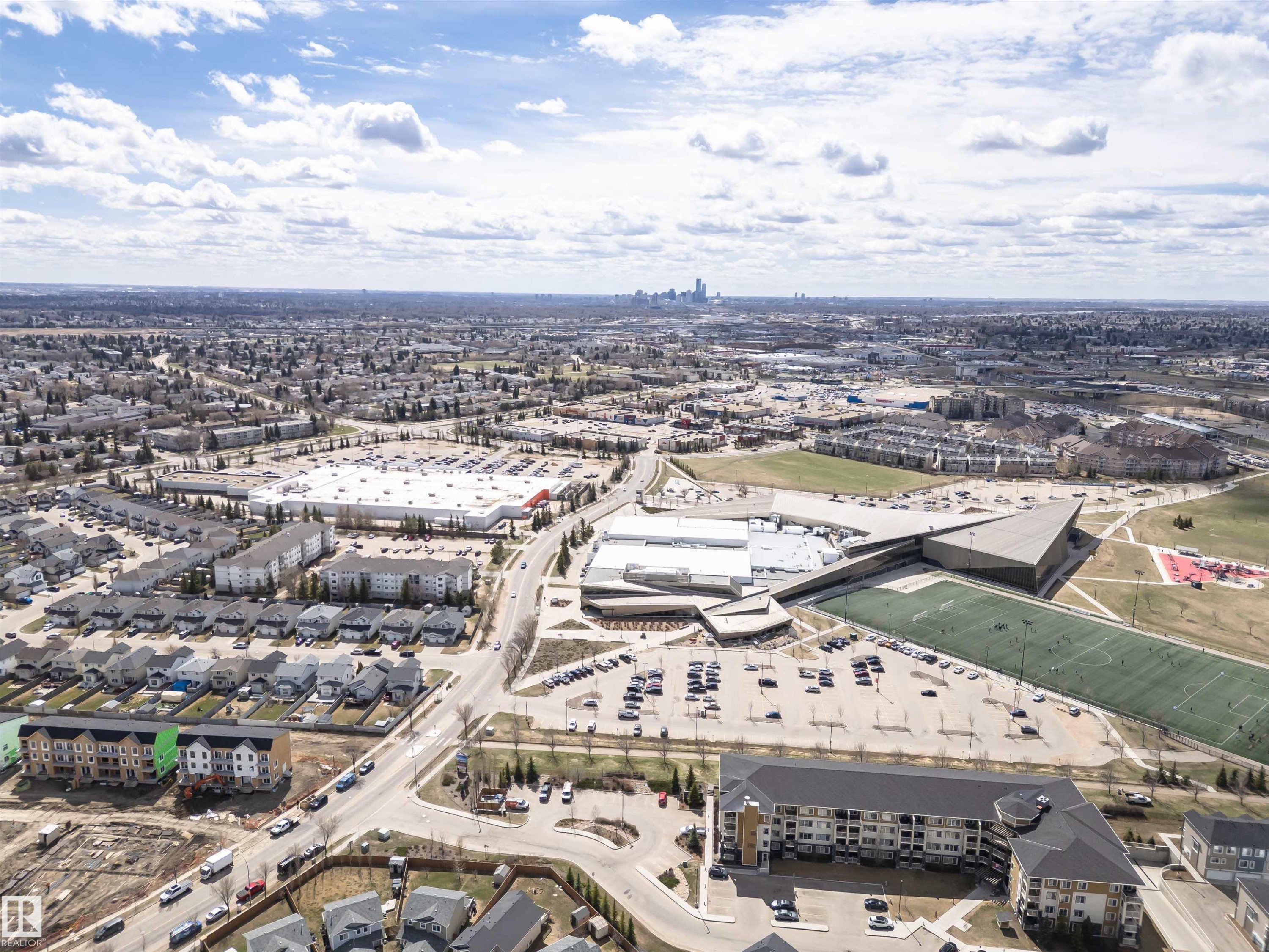 Aerial perspective showcasing a mixed-use neighborhood with residential properties, commercial retail centers, and recreational facilities - #110 3625 144 Av Nw, Edmonton, AB - Outdoor With View