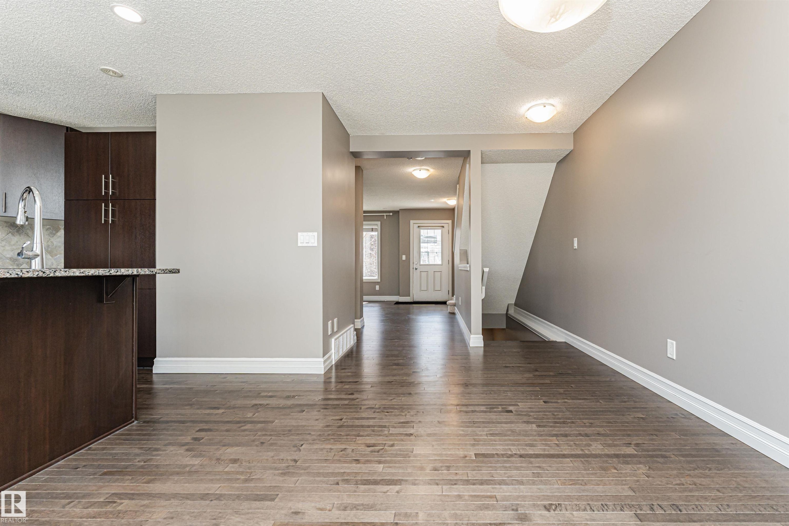 Open concept living area with wood-finish flooring - #110 3625 144 Av Nw, Edmonton, AB - Indoor