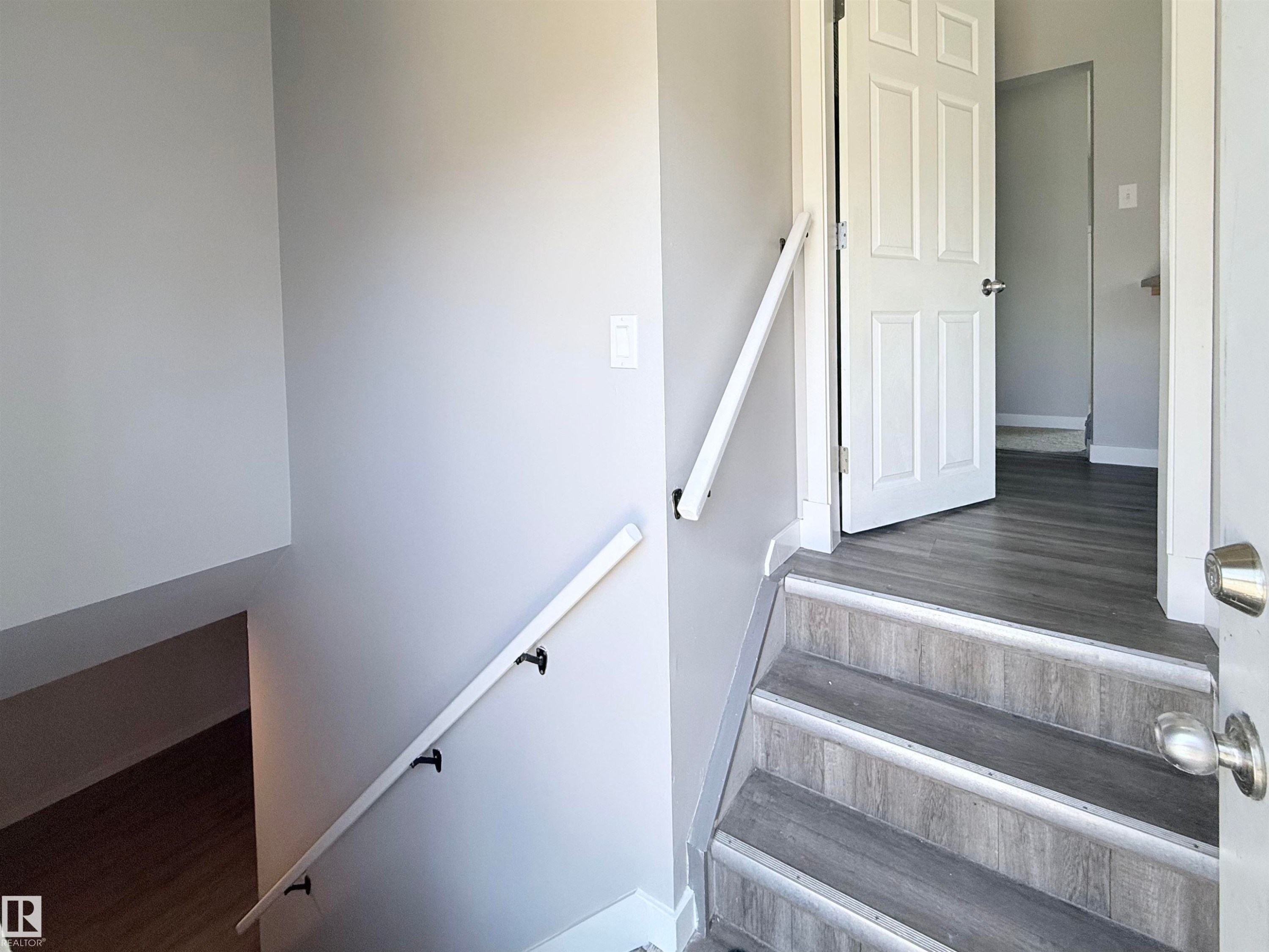 Side entrance, Staircase featuring wood-finish treads, risers, and handrails with matte black brackets - 3912 108 Street, Edmonton, AB - Indoor Photo Showing Other Room