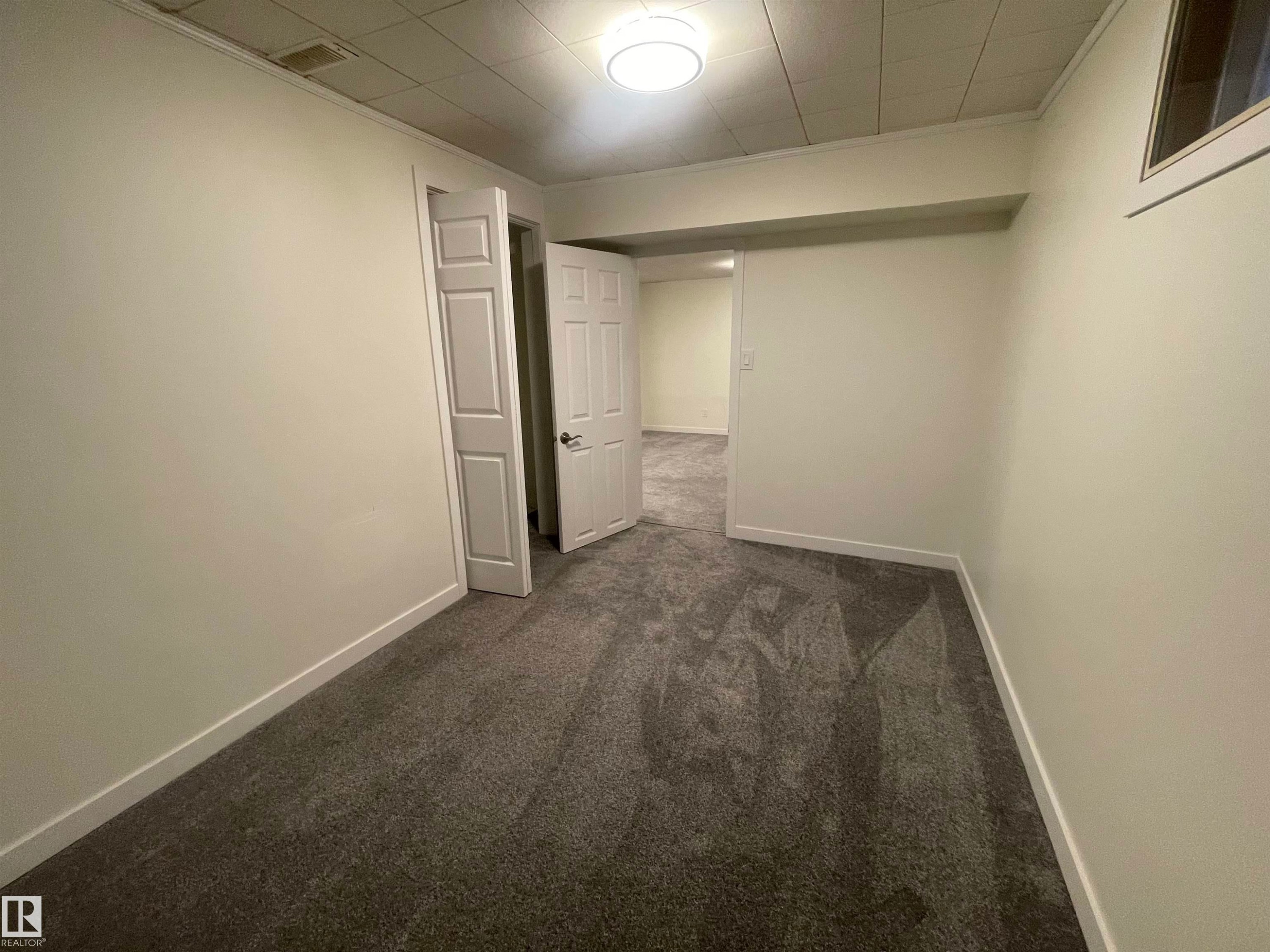 Interior room featuring neutral wall paint, gray patterned carpet, a white paneled door, a flush-mount ceiling light, and white baseboards - 13804 132 Avenue, Edmonton, AB - Indoor Photo Showing Other Room