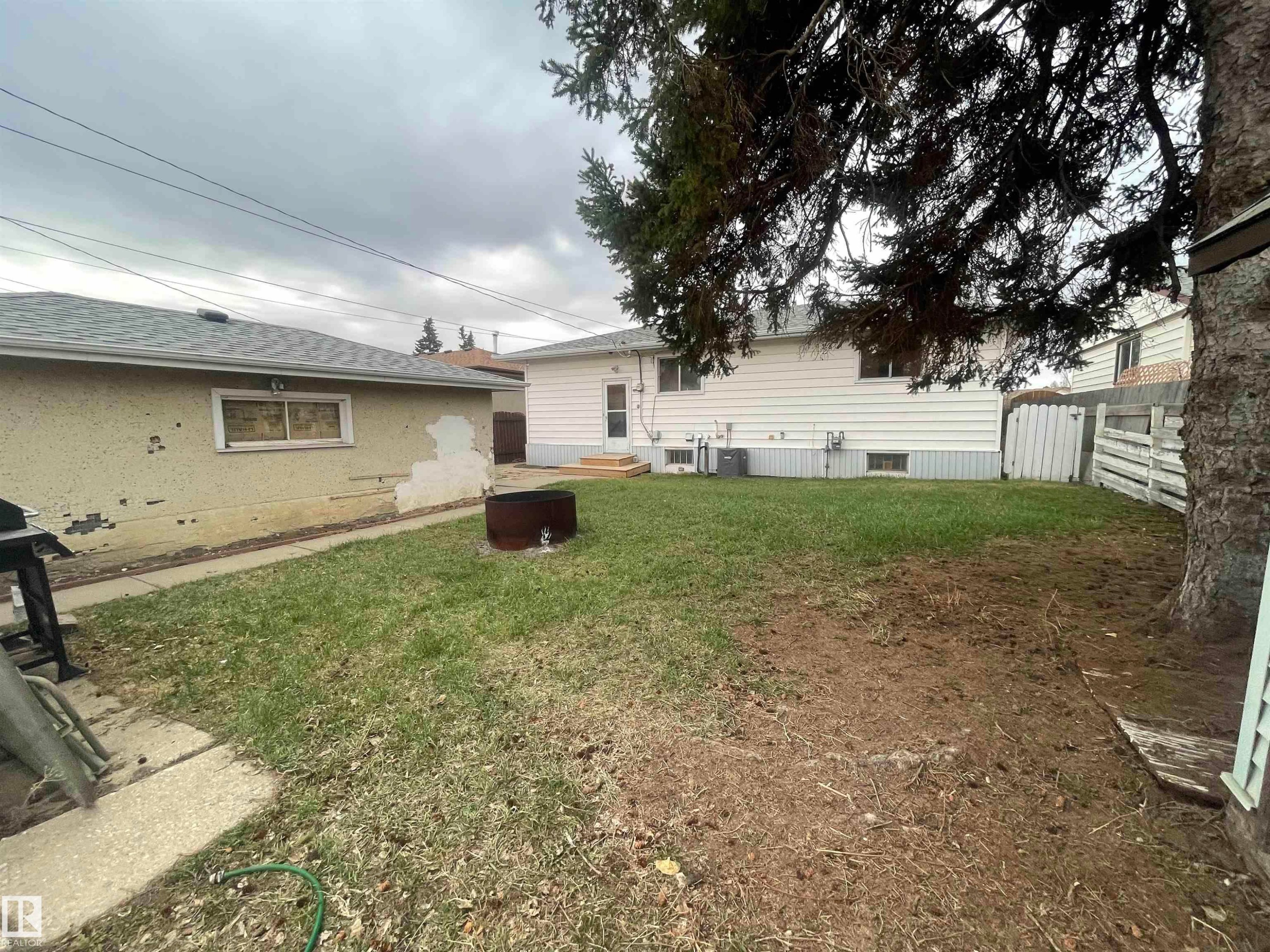 Spacious backyard featuring a grass lawn, white siding exterior, and mature tree - 13804 132 Avenue, Edmonton, AB - Outdoor