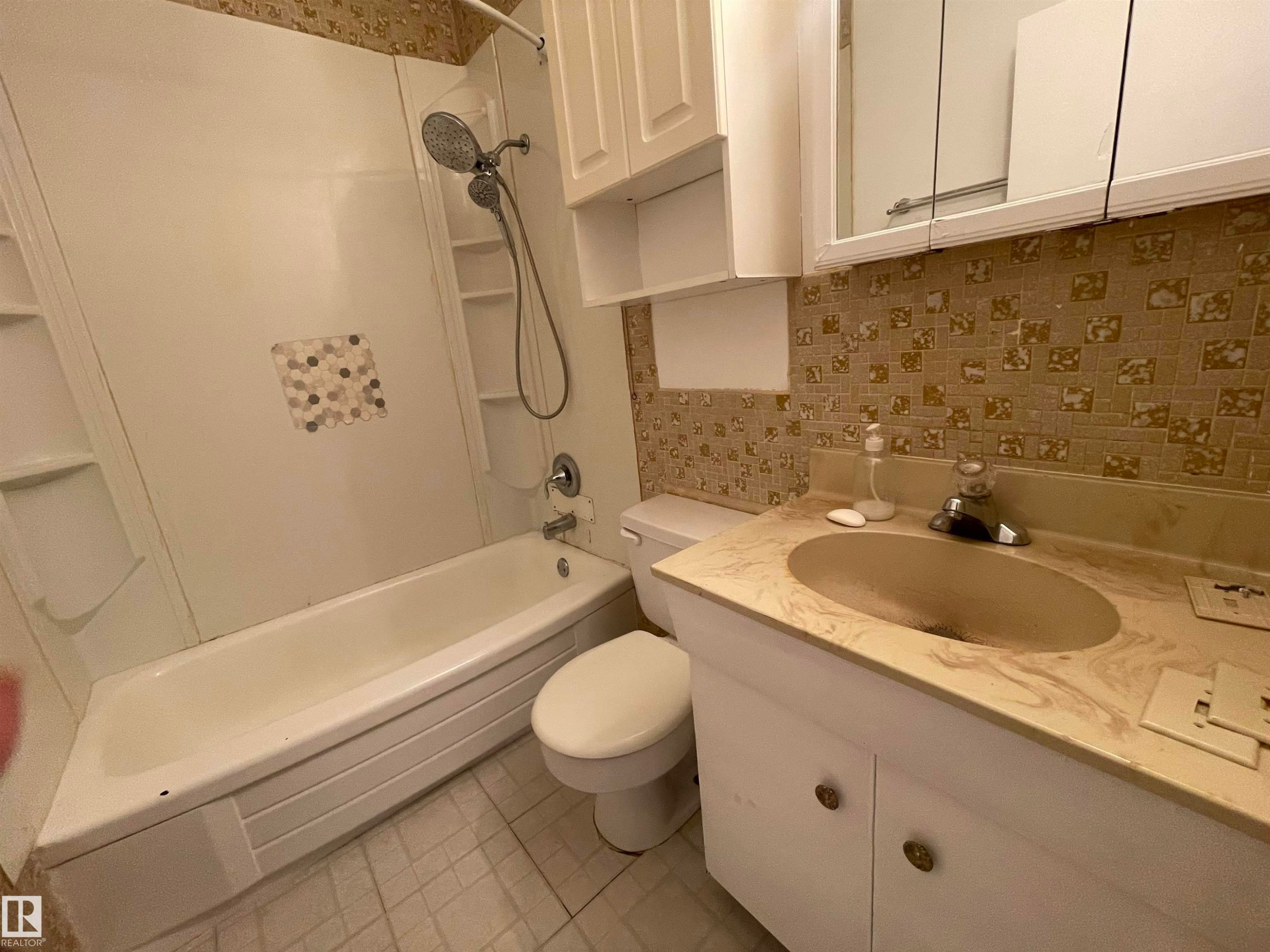 Bathroom featuring a white bathtub, shower with built-in shelving, vanity with integrated sink, and upper cabinetry with mirrored medicine cabinet - 13804 132 Avenue, Edmonton, AB - Indoor Photo Showing Bathroom