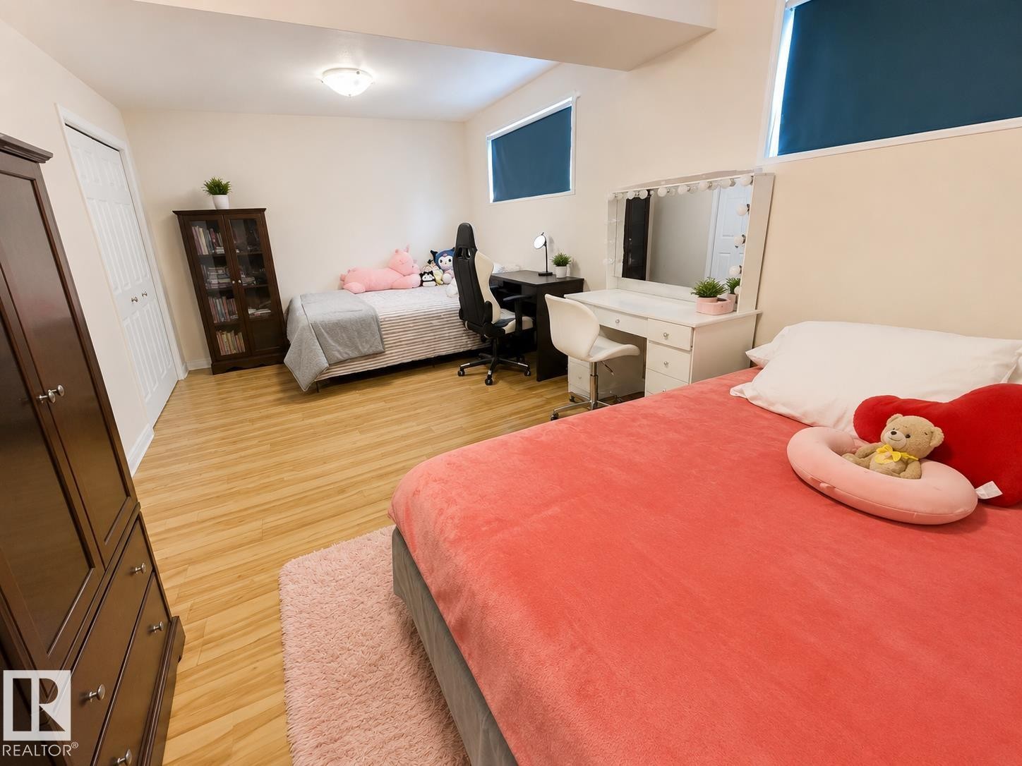 Spacious room featuring wood-finish flooring, white walls, and two windows with dark roller blinds - 5712 101 Avenue, Edmonton, AB - Indoor Photo Showing Bedroom