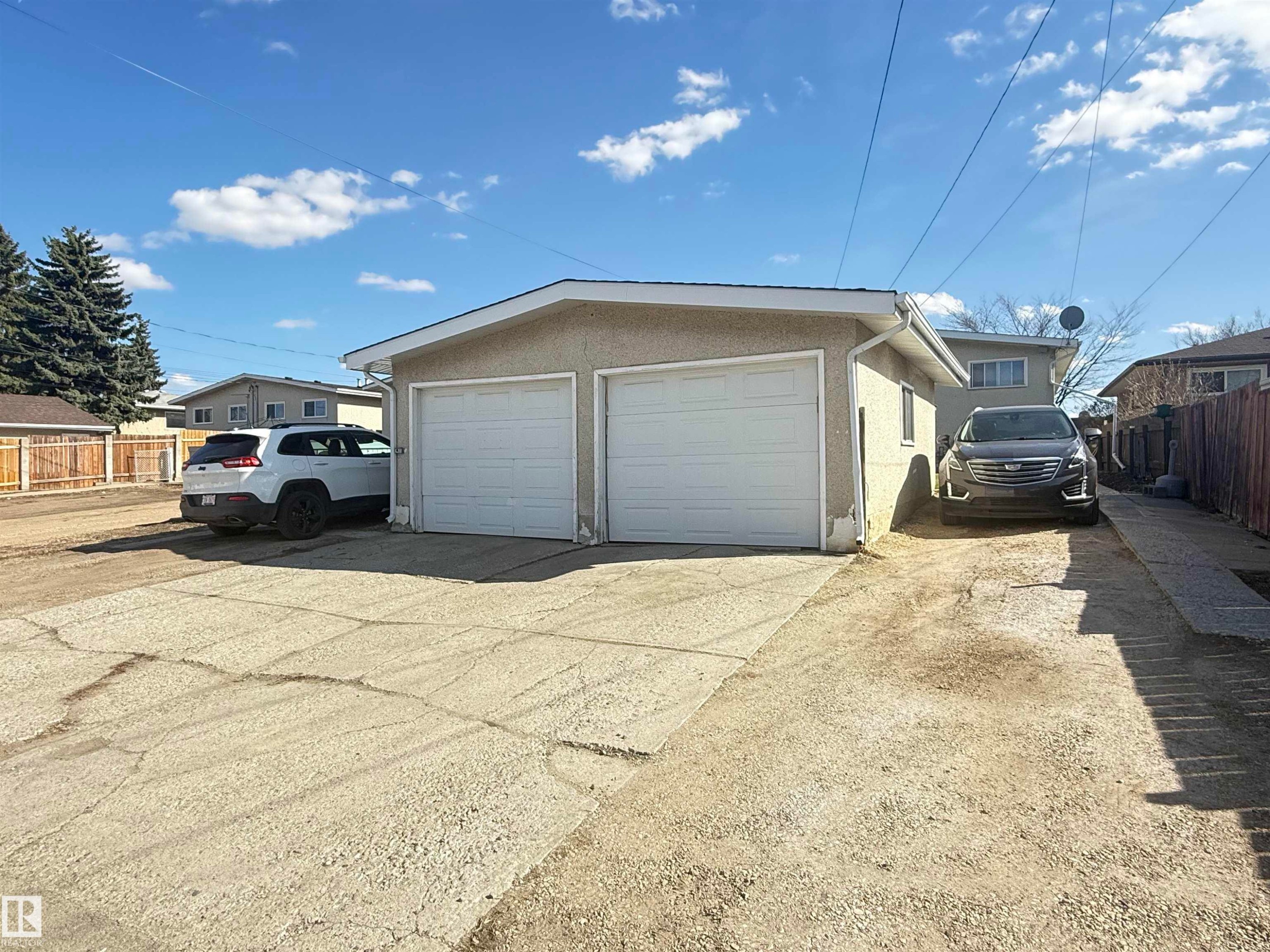 Detached garage featuring two overhead doors, stucco exterior, and a shingled roof - 5712 101 Avenue, Edmonton, AB - Outdoor With Exterior