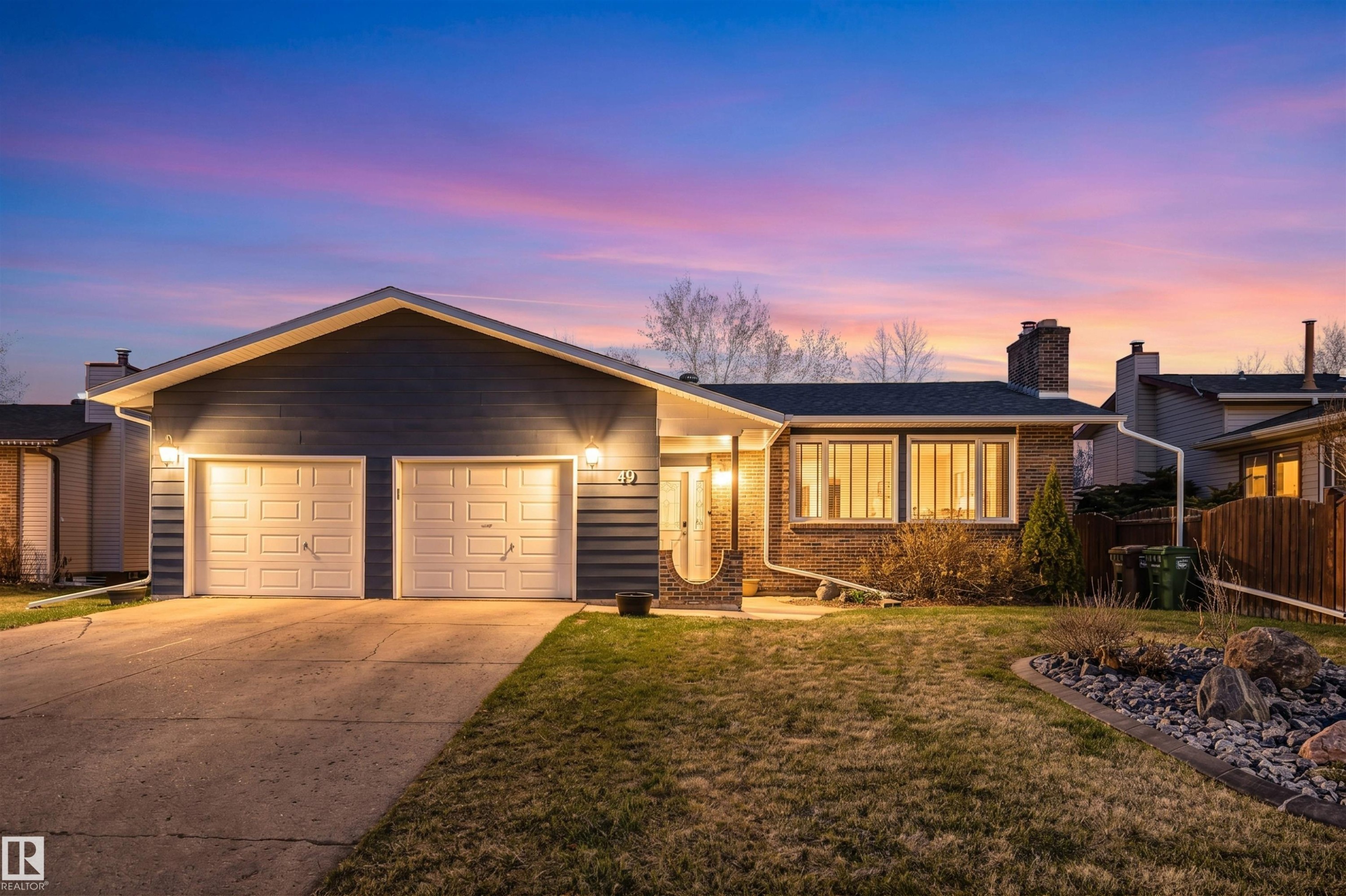 Ranch-style residence featuring a two-car garage with overhead lighting, a concrete driveway, and a combination of horizontal siding and brick facade - 49 Ash Crescent, St. Albert, AB - Outdoor
