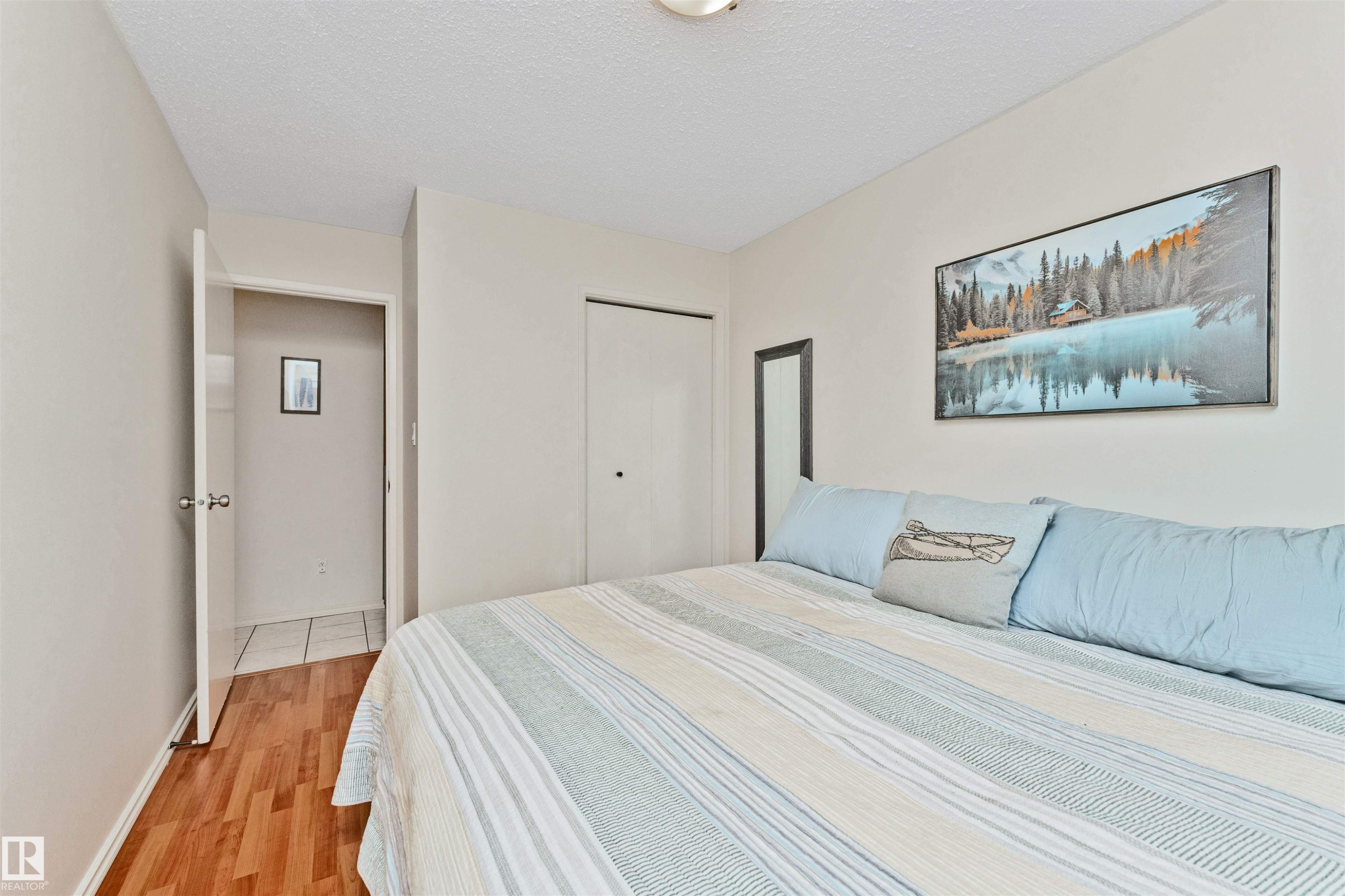 Bedroom featuring wood-finish flooring, neutral wall tones, and a built-in closet with bi-fold doors - 49 Ash Crescent, St. Albert, AB - Indoor Photo Showing Bedroom