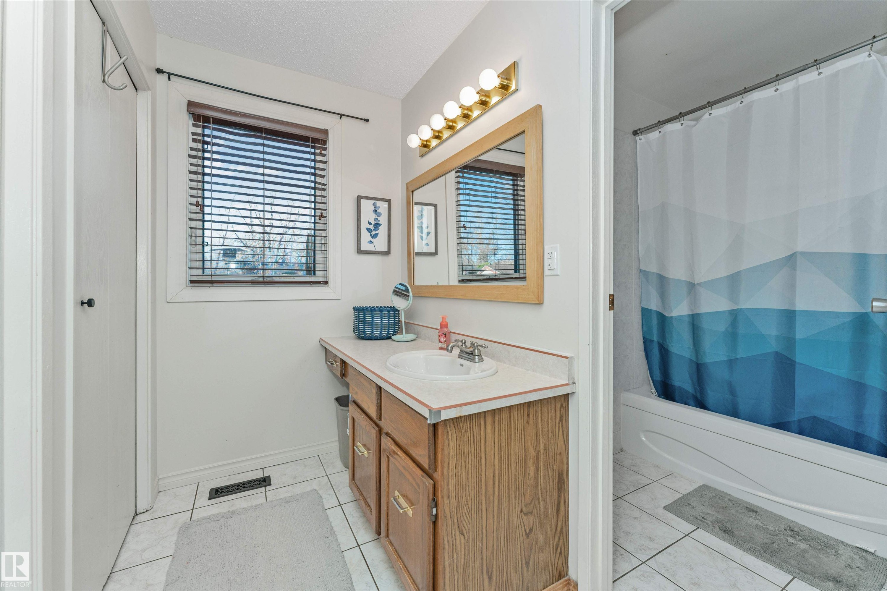 Bathroom featuring a wood-finish vanity with a single basin sink and laminate countertop - 49 Ash Crescent, St. Albert, AB - Indoor Photo Showing Bathroom