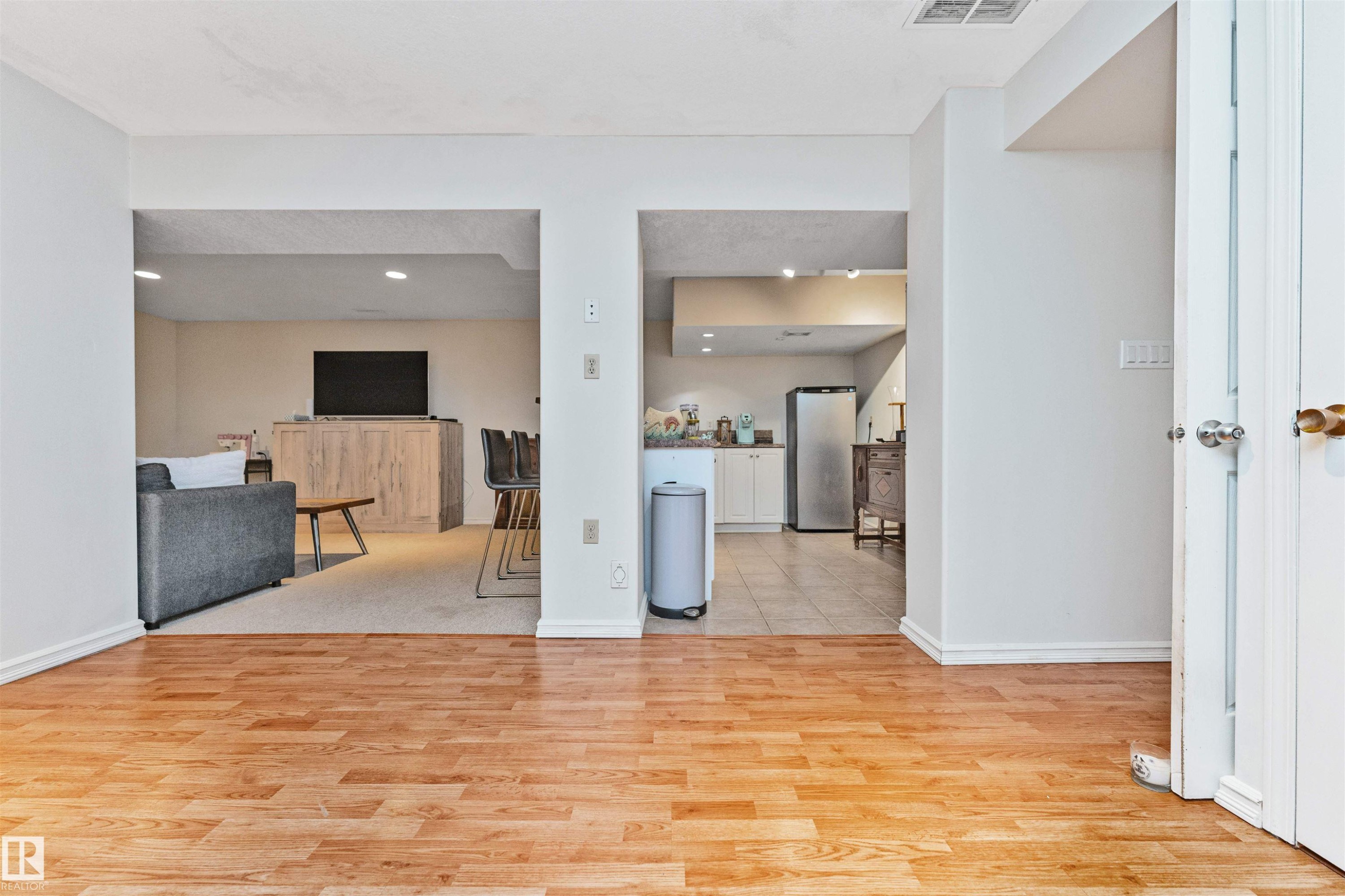 Wood-finish flooring throughout the foreground leading to distinct open archways - 49 Ash Crescent, St. Albert, AB - Indoor Photo Showing Other Room