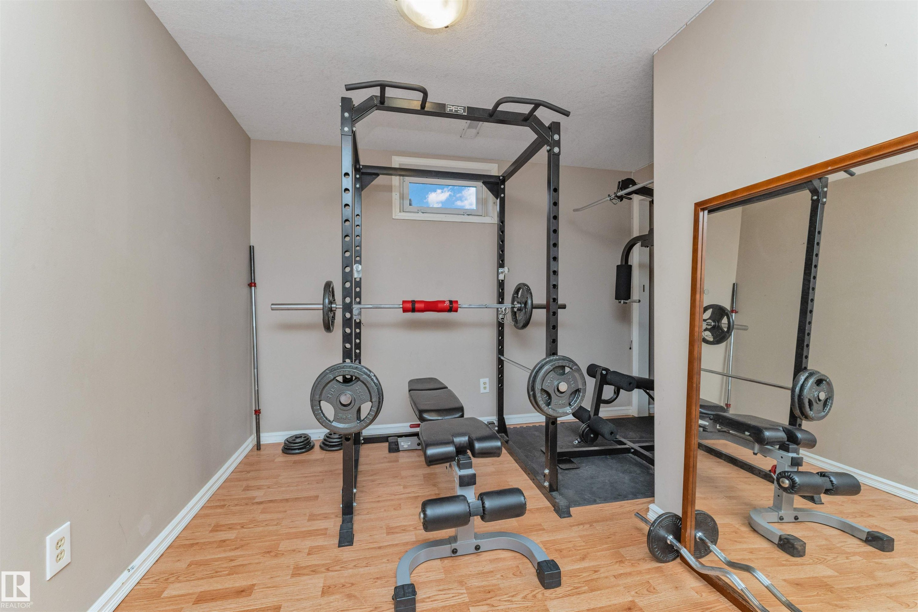 Dedicated exercise room featuring wood-finish flooring, neutral wall tones, and a built-in window providing natural light - 49 Ash Crescent, St. Albert, AB - Indoor Photo Showing Gym Room