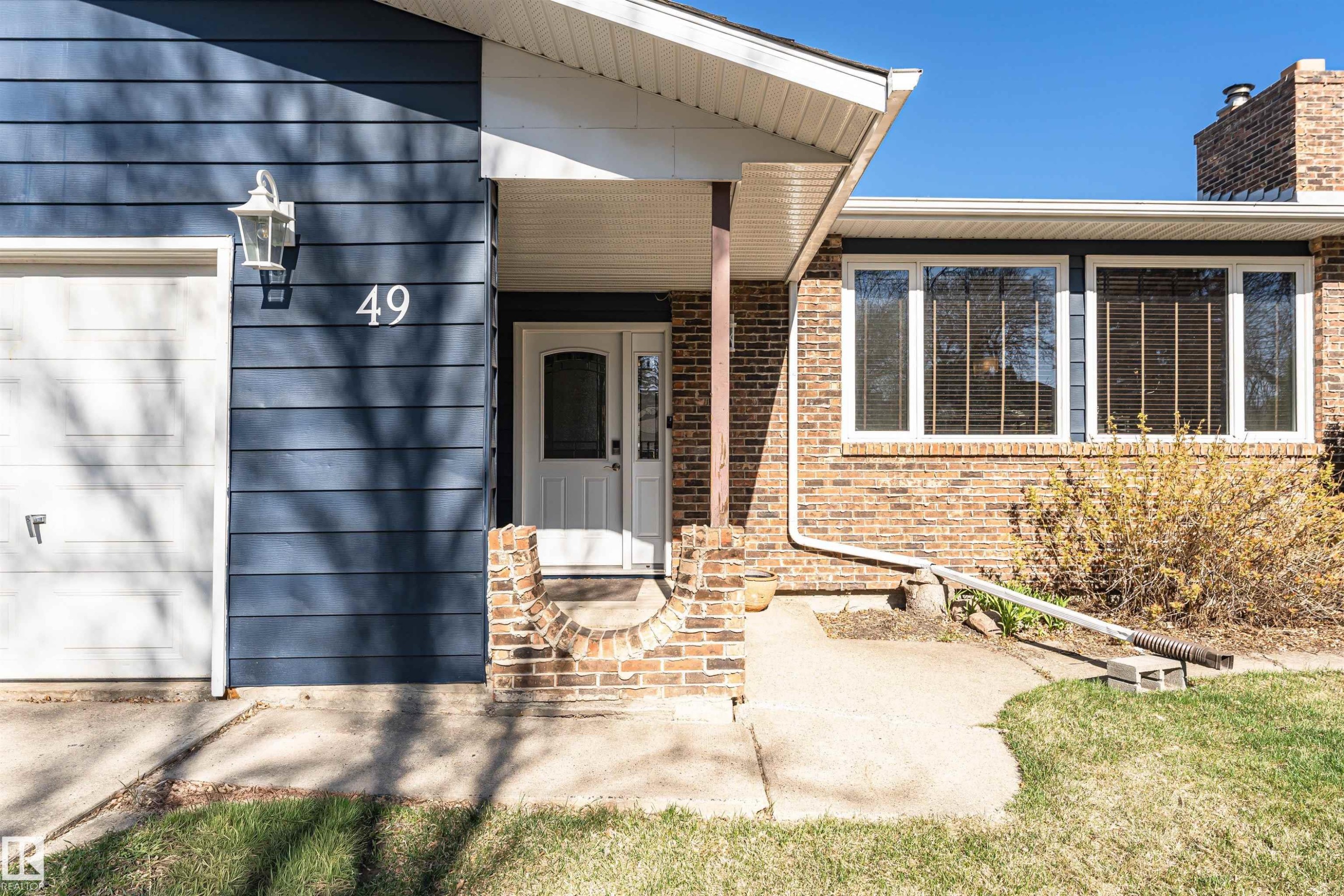 Front exterior featuring blue horizontal siding and brick accents - 49 Ash Crescent, St. Albert, AB - Outdoor