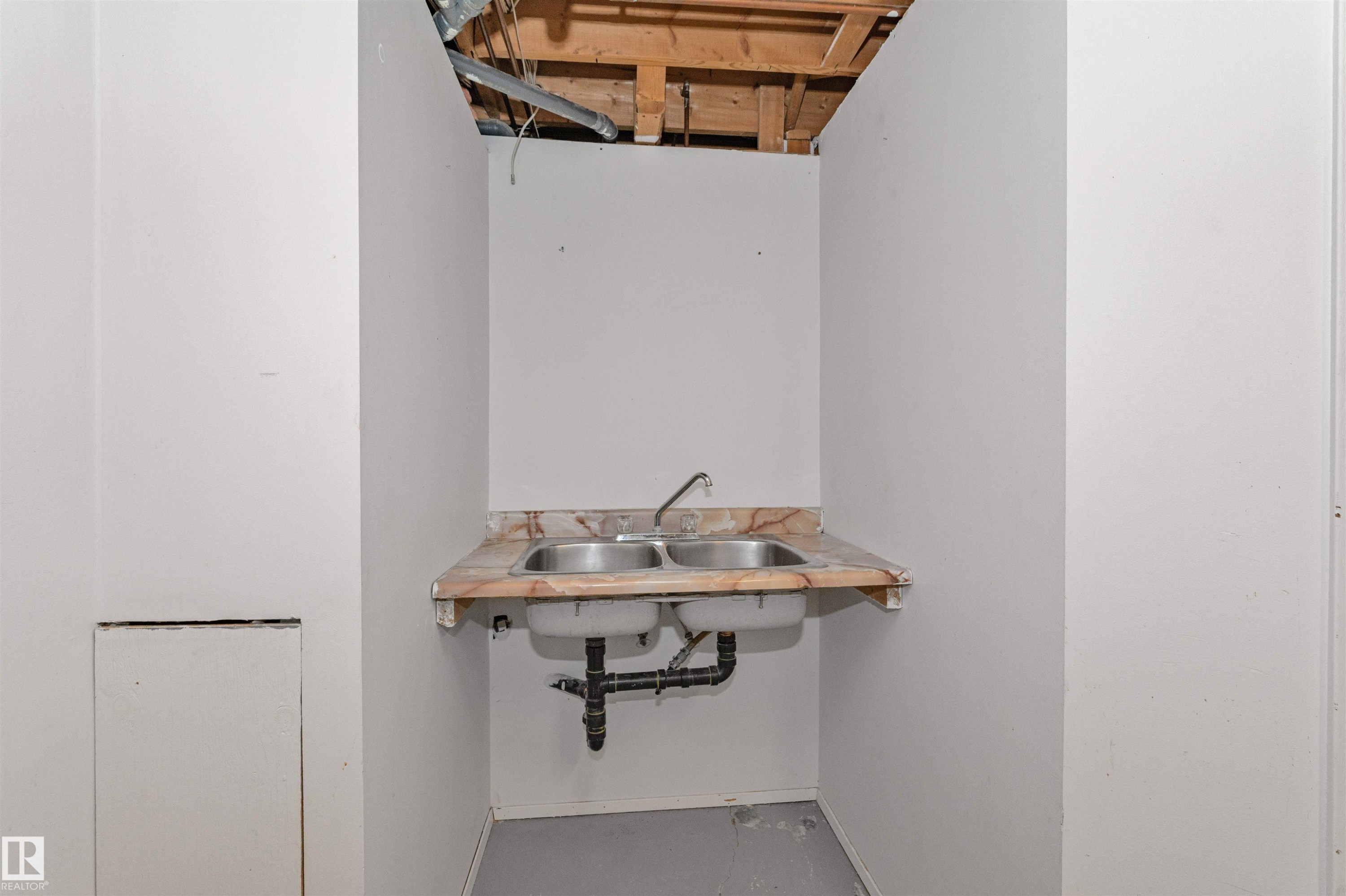 Utility sink area featuring a dual stainless steel sink, a patterned countertop, and exposed overhead joists - 49 Ash Crescent, St. Albert, AB - Indoor Photo Showing Other Room