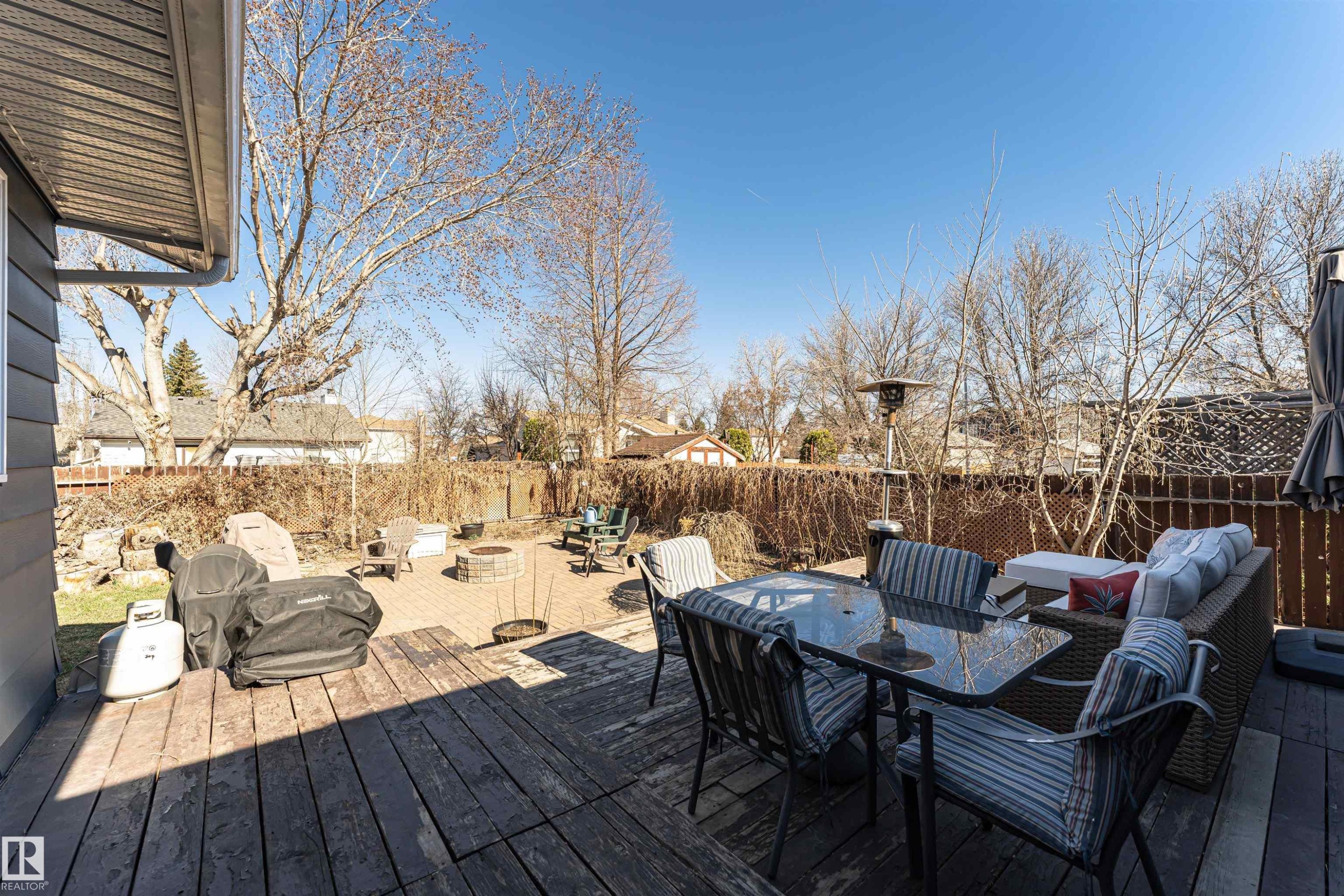 Expansive backyard featuring a multi-level deck with wood-finish flooring, a paver patio, and surrounding privacy fencing - 49 Ash Crescent, St. Albert, AB - Outdoor With Deck Patio Veranda