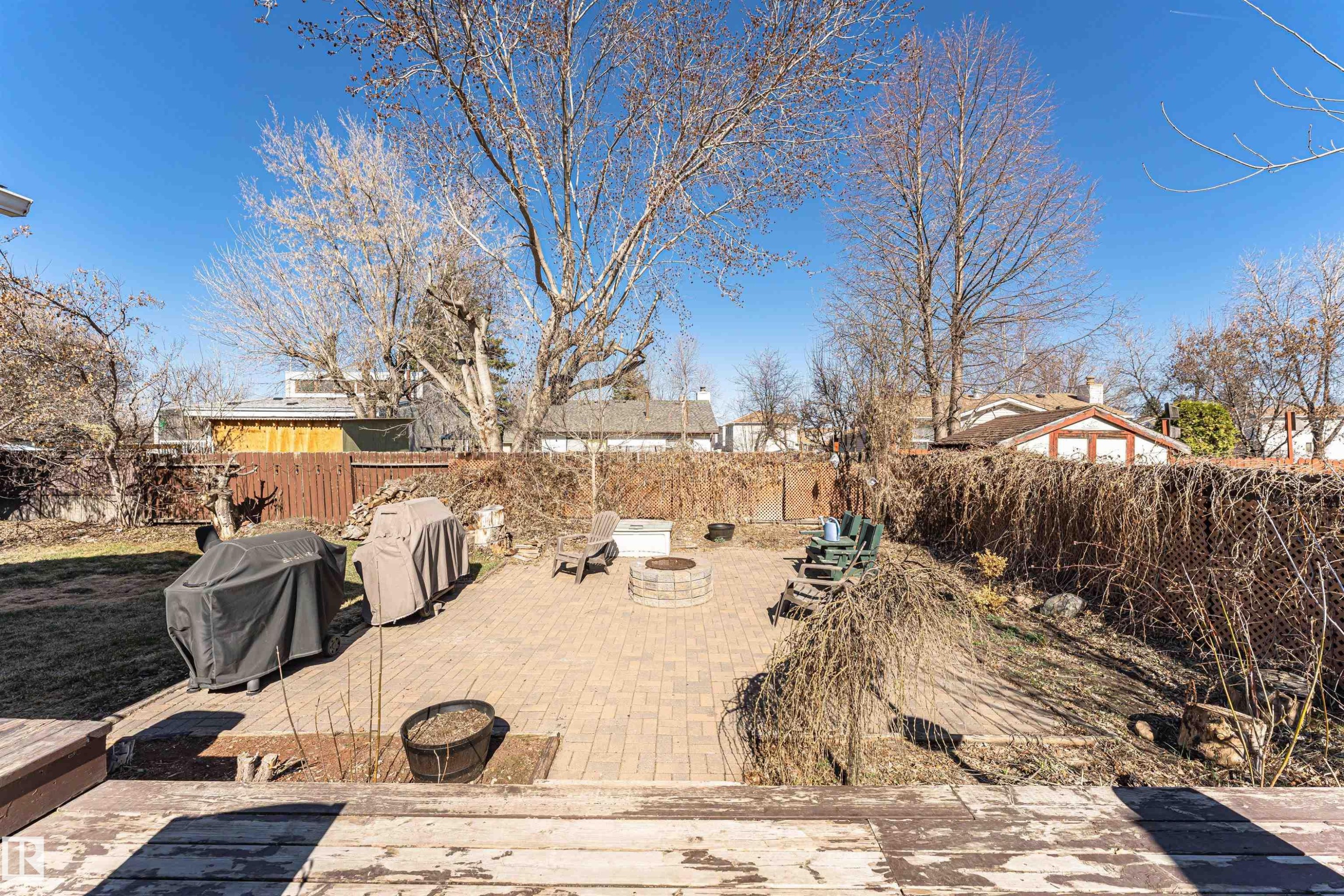 Spacious outdoor patio with paver flooring, a built-in fire pit, and mature trees - 49 Ash Crescent, St. Albert, AB - Outdoor