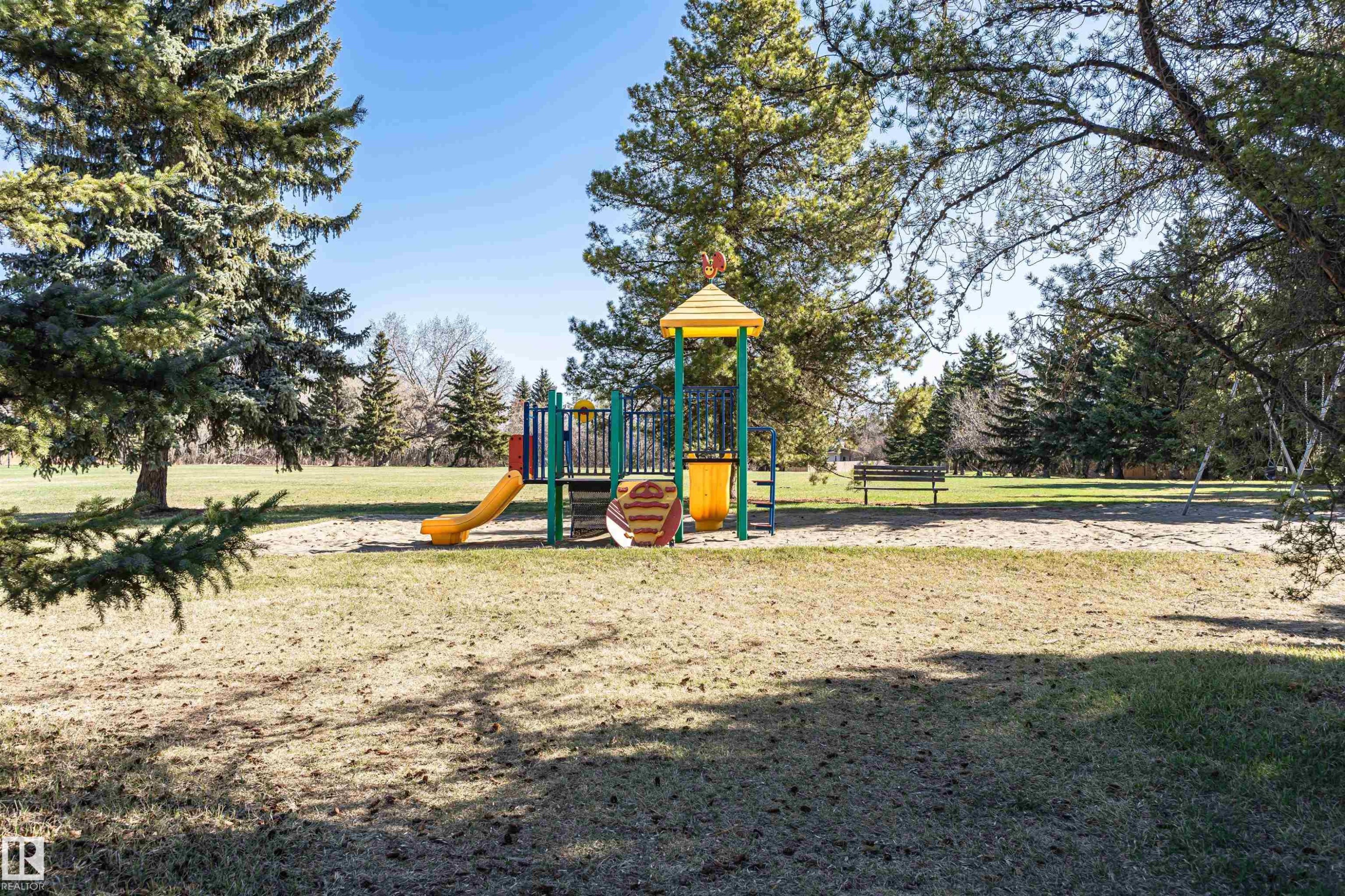Park playground featuring a yellow slide, colorful climbing structure, and sand base - 49 Ash Crescent, St. Albert, AB - Outdoor