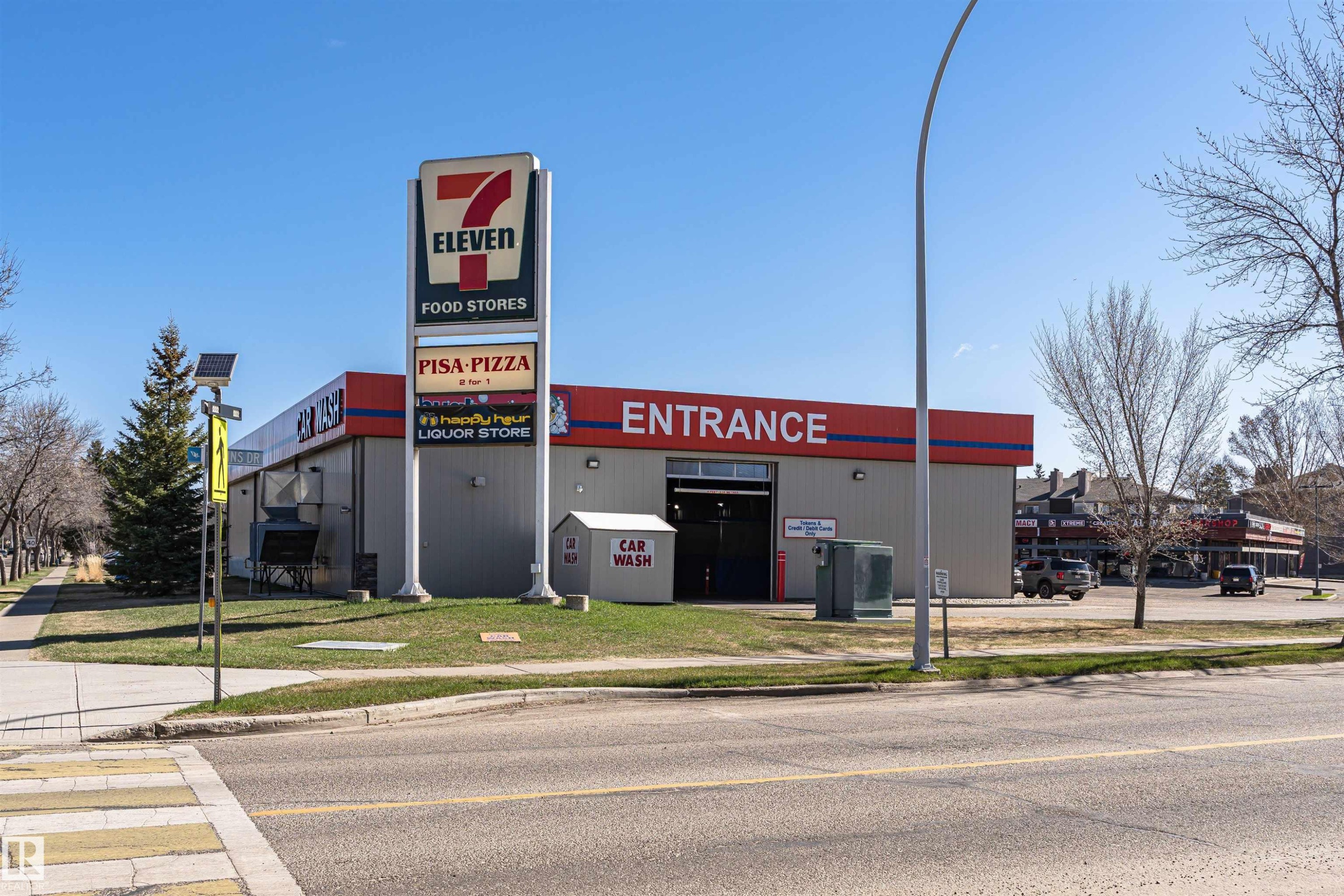 Commercial building featuring a prominent 7-Eleven sign, Pisa Pizza signage, and a liquor store sign - 49 Ash Crescent, St. Albert, AB - Outdoor
