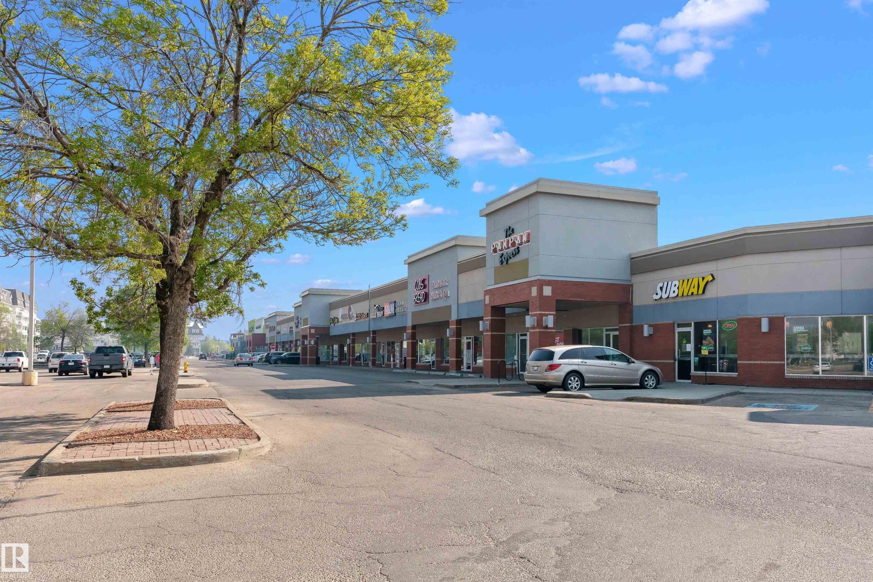 Retail strip center featuring a brick facade with stone accents and multiple storefronts - 49 Ash Crescent, St. Albert, AB - Outdoor