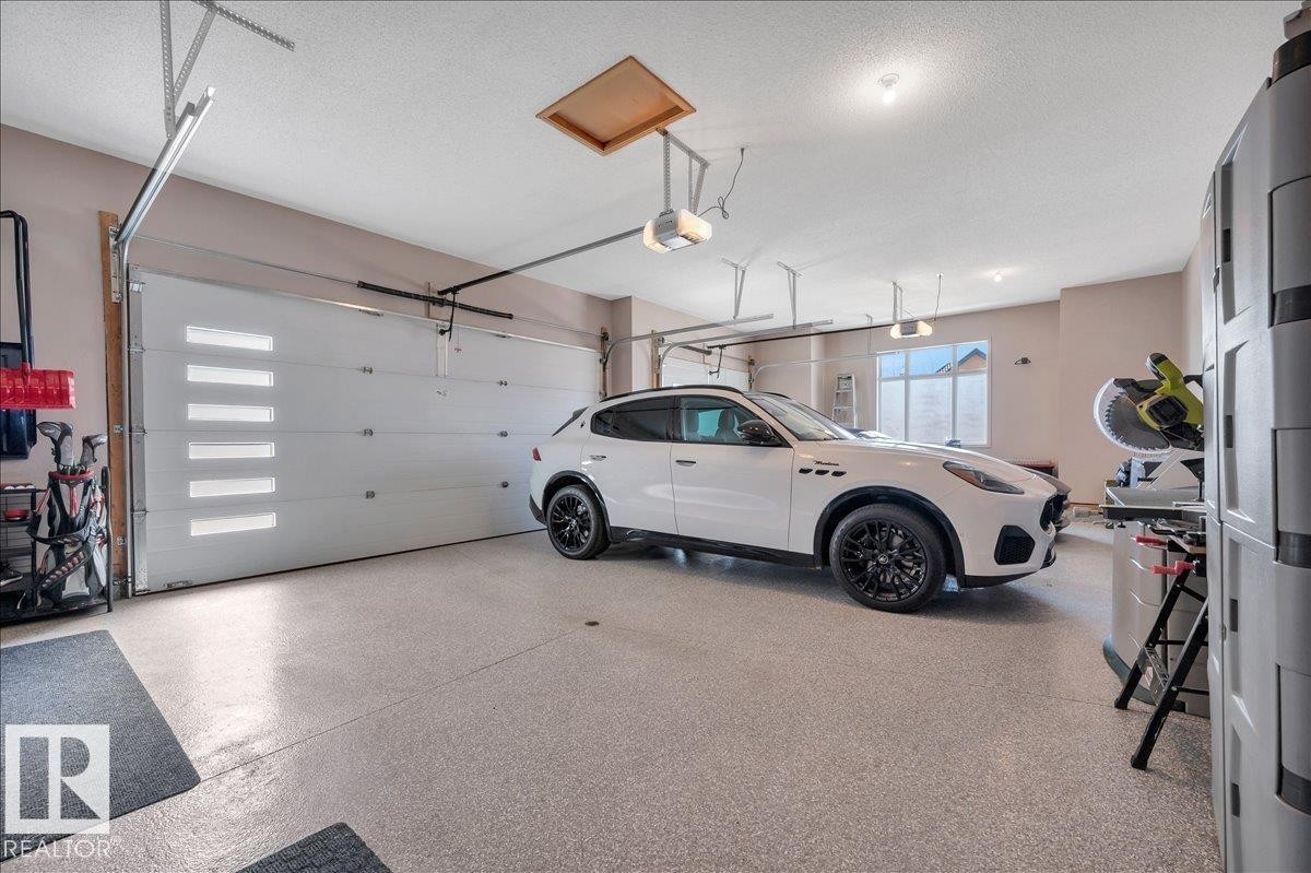 OVERSIZED TRIPLE GARAGE WITH EPOXY FLOOR, DRYWALLED, PAINTED, TEXTURED CEILING, FLOOR DRAIN, GAS HEATER, LEVEL 2 VEHICLE CHARGER AND HEIGHT FOR VEHICLE LIFTS - 314 Weaver Point(E), Edmonton, AB - Indoor Photo Showing Garage