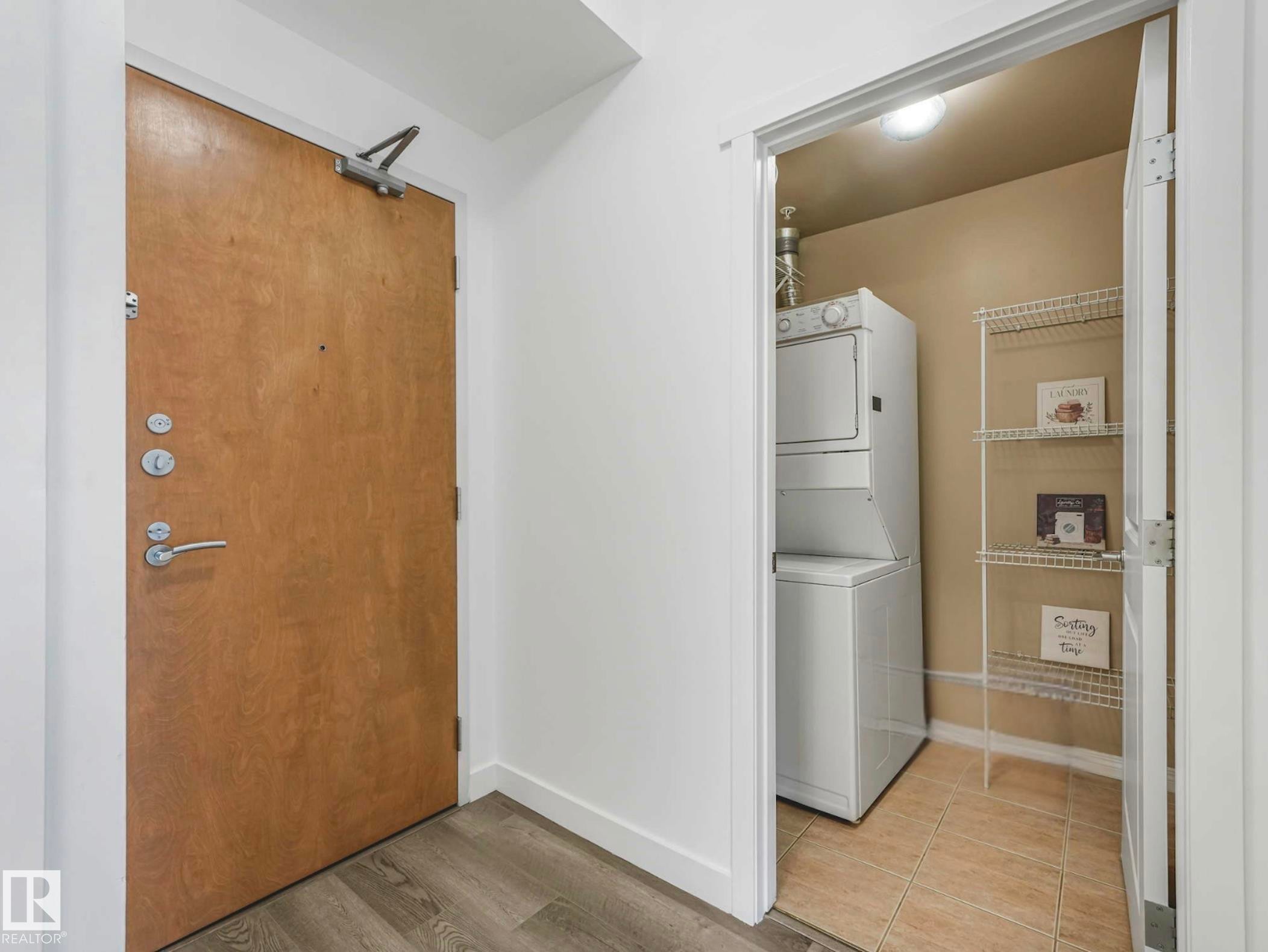 Entryway featuring wood-finish flooring and a laundry closet with stacked appliances, tile flooring, and wire shelving - 305 10504 99 Avenue, Edmonton, AB - Indoor Photo Showing Laundry Room