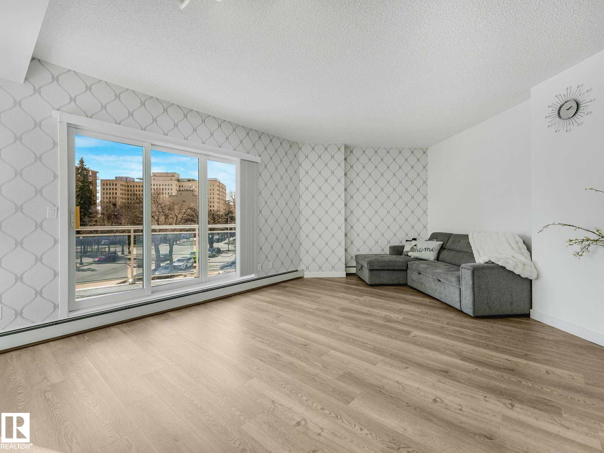 Living area featuring light wood-finish flooring and a full-width sliding glass door - 305 10504 99 Avenue, Edmonton, AB - Indoor