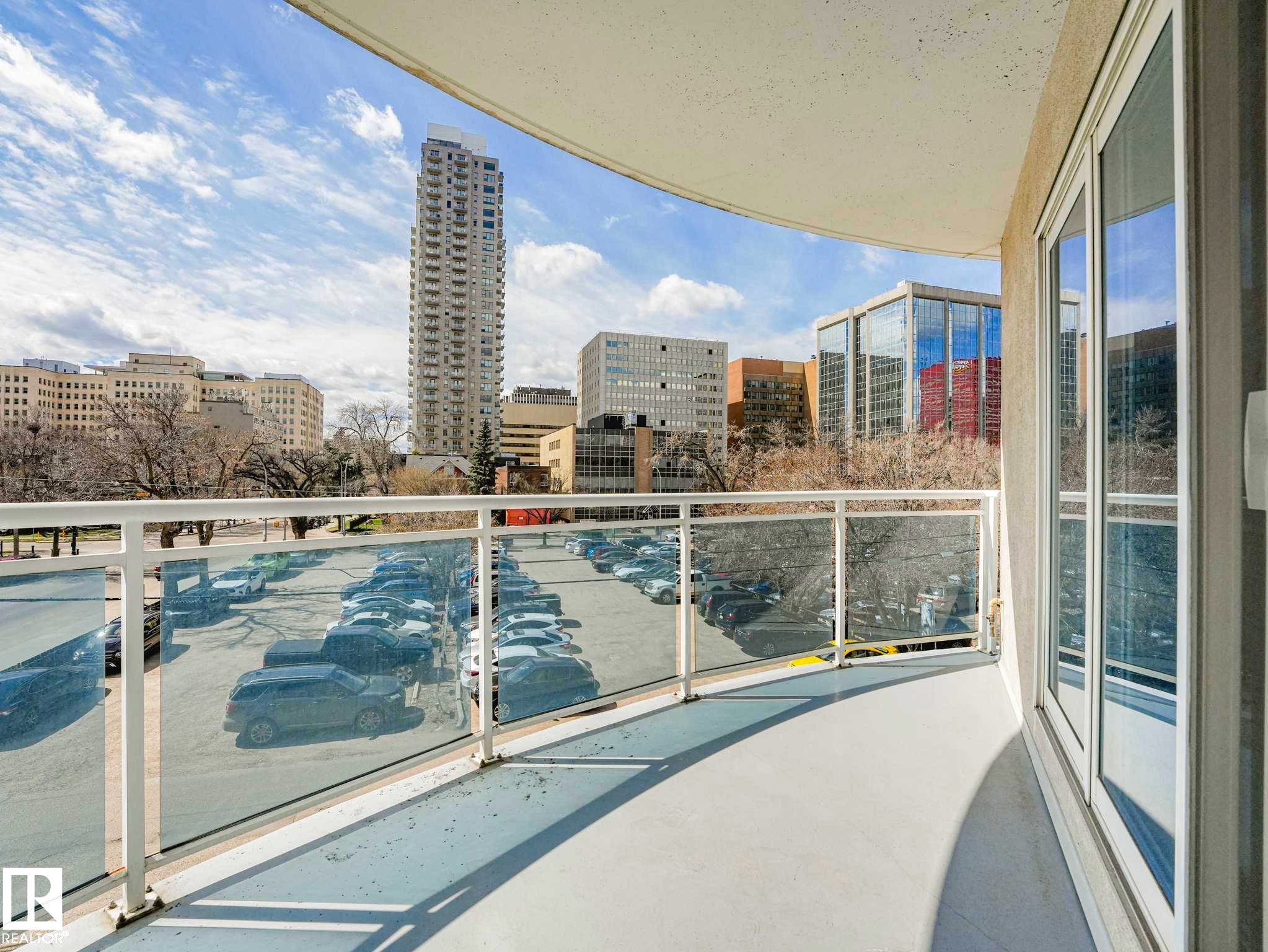 Curved balcony featuring glass railing panels, white metal framing, and a concrete floor - 305 10504 99 Avenue, Edmonton, AB - Outdoor With Balcony