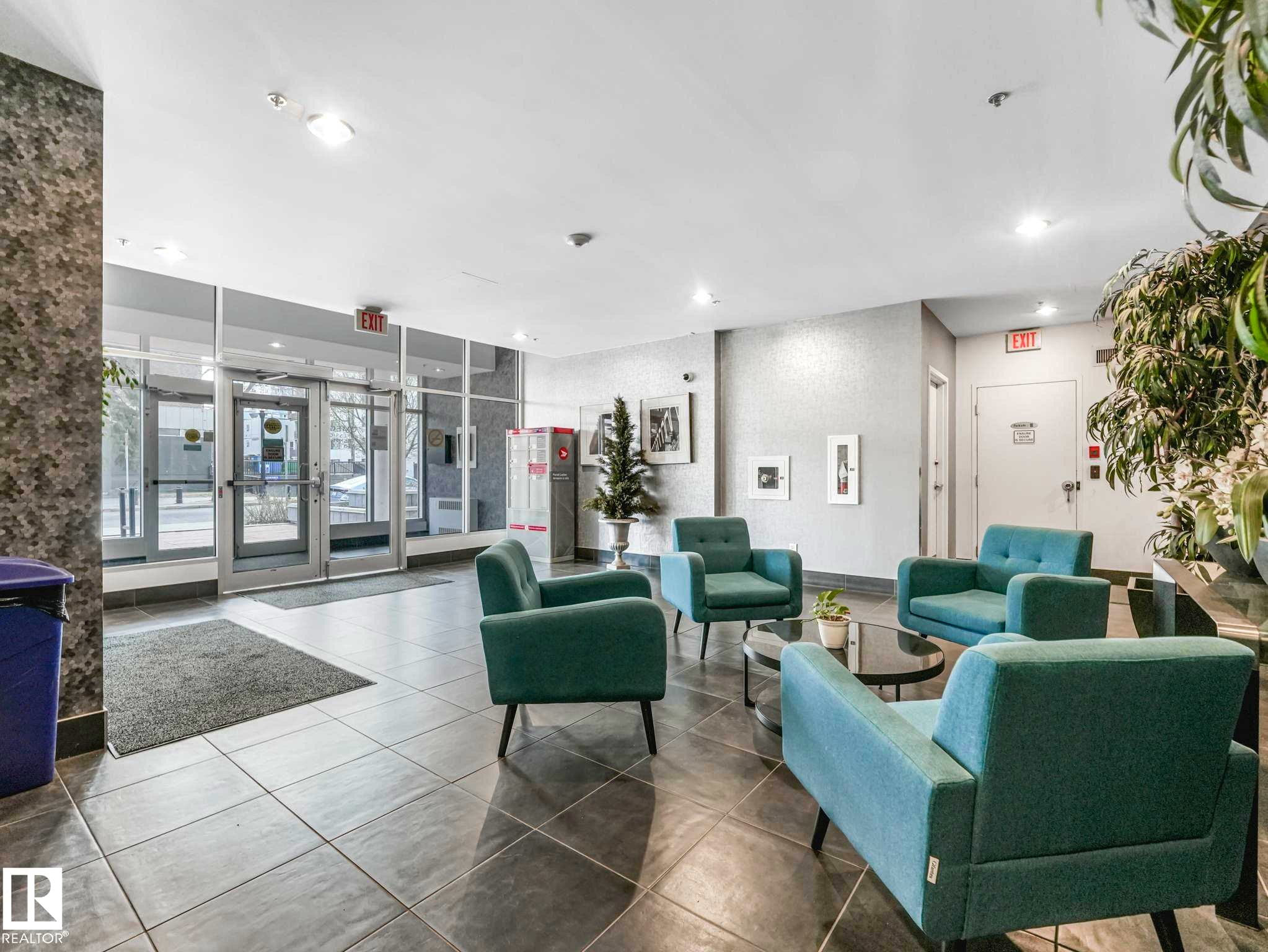 Lobby entrance featuring large format tile flooring, full-height glass entry doors, and a textured accent wall - 305 10504 99 Avenue, Edmonton, AB - Indoor