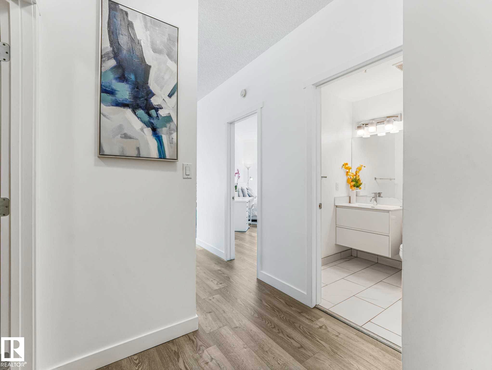 Hallway with wood-finish flooring and white baseboards - 305 10504 99 Avenue, Edmonton, AB - Indoor