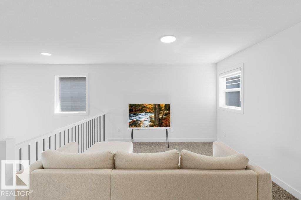 Open concept living area featuring clean white walls, neutral carpeting, recessed ceiling lighting, a contemporary white railing, and multiple windows with blinds - 19110 20A Avenue, Edmonton, AB - Indoor Photo Showing Living Room