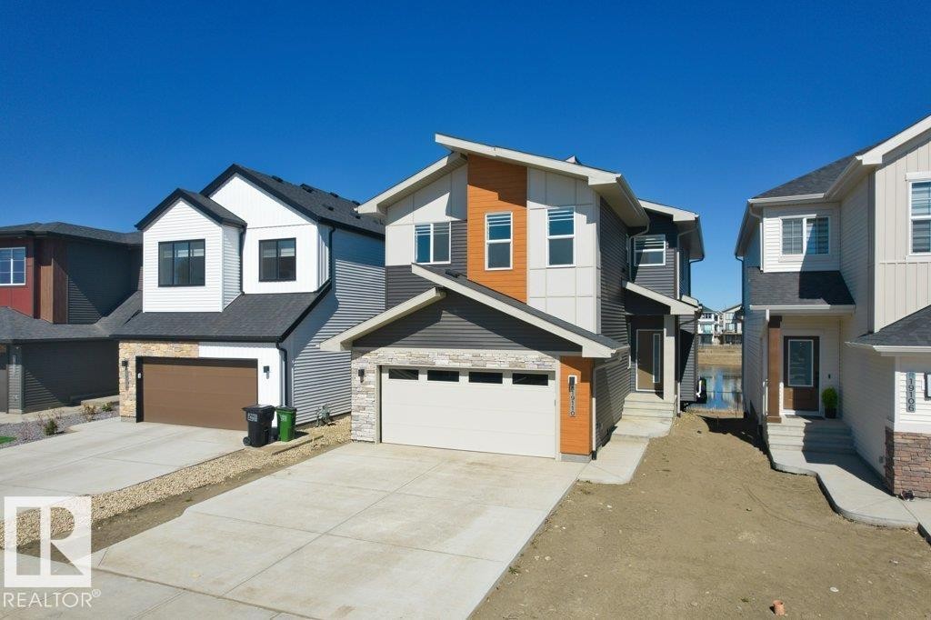Modern exterior showcasing multi-tone siding, stone accents, and a dual-panel garage door - 19110 20A Avenue, Edmonton, AB - Outdoor With Facade