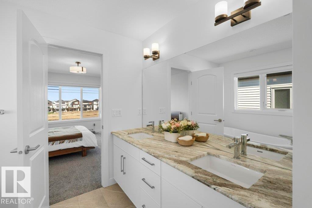 Double vanity with a granite countertop, undermount sinks, and chrome faucets - 19110 20A Avenue, Edmonton, AB - Indoor Photo Showing Bathroom