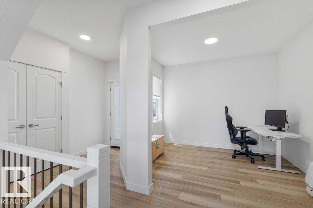 Open concept living area featuring wood-finish flooring, recessed lighting, white walls, and a white painted railing with black spindles - 19110 20A Avenue, Edmonton, AB - Indoor