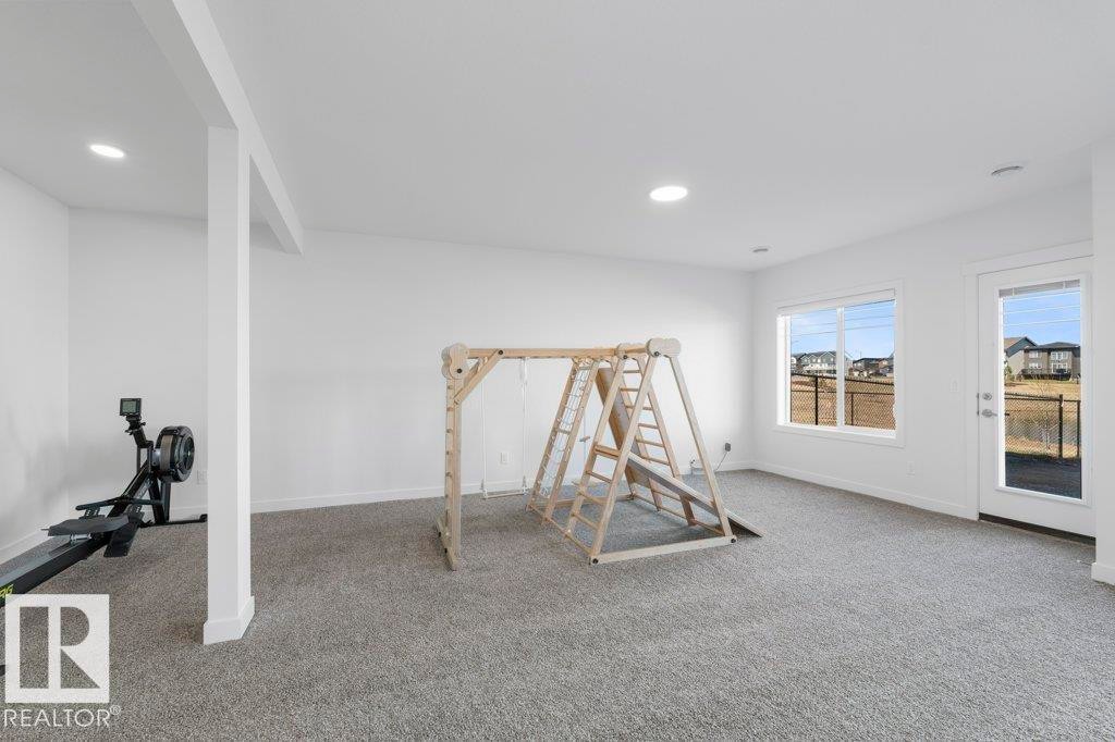 Spacious room featuring light gray carpeting, recessed lighting, and a white interior column - 19110 20A Avenue, Edmonton, AB - Indoor