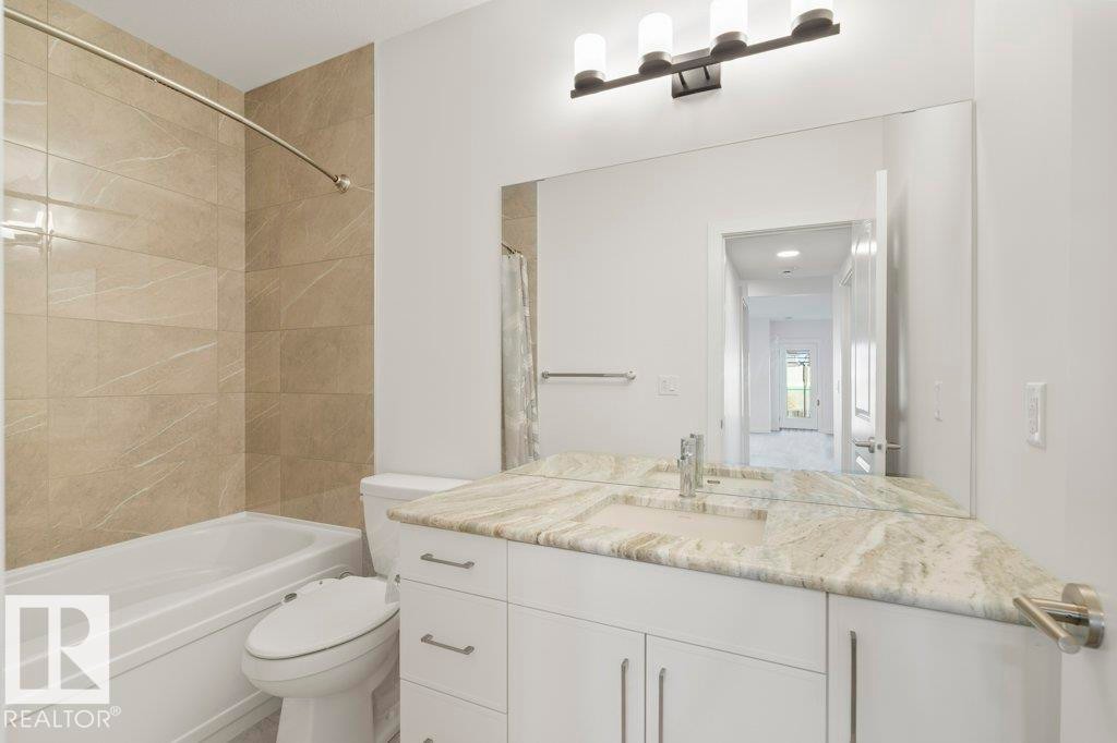 Bathroom featuring a white vanity with slab-front cabinetry, a single undermount sink, and a light-toned, patterned countertop - 19110 20A Avenue, Edmonton, AB - Indoor Photo Showing Bathroom