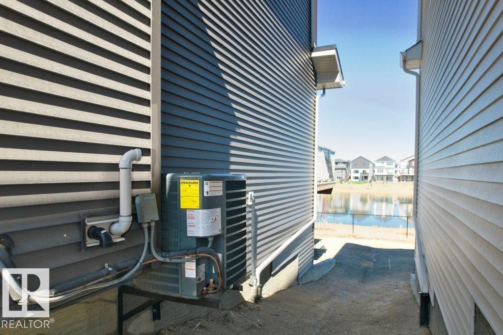 Exterior of a property featuring horizontal siding, an HVAC unit, and drainage pipes - 19110 20A Avenue, Edmonton, AB - Outdoor