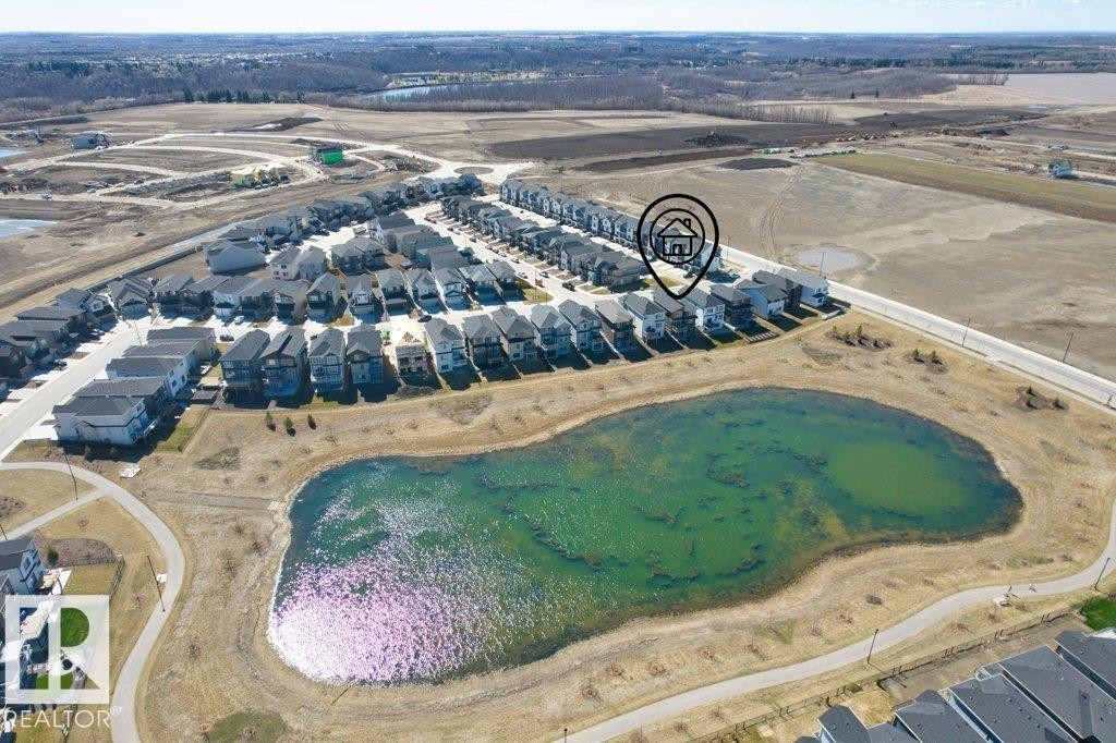 Aerial landscape featuring a residential development with a prominent pond and paved walking paths - 19110 20A Avenue, Edmonton, AB - Outdoor With View
