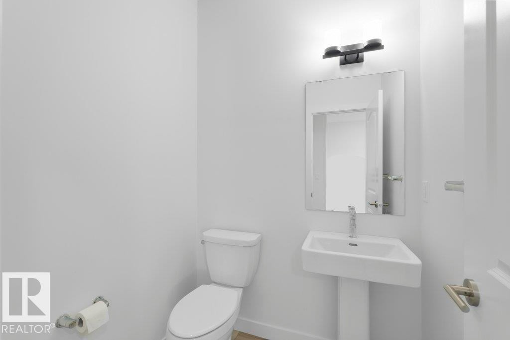White pedestal sink with a rectangular basin, chrome faucet, and rectangular mirror - 19110 20A Avenue, Edmonton, AB - Indoor Photo Showing Bathroom