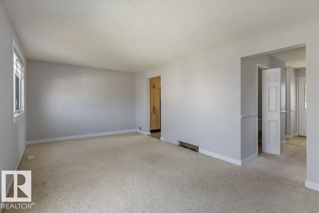 Spacious room featuring light gray walls, textured carpet flooring, and a single window with white trim - 3736 12 Avenue, Edmonton, AB - Indoor Photo Showing Other Room