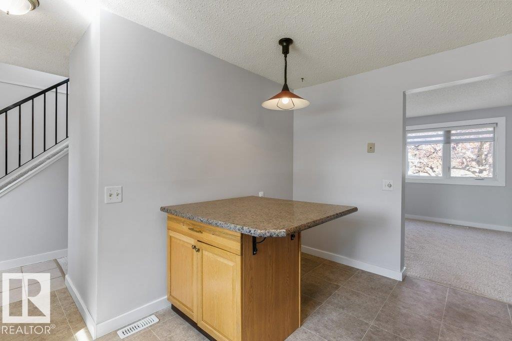 Kitchen island featuring wood cabinetry and a speckled countertop - 3736 12 Avenue, Edmonton, AB - Indoor Photo Showing Other Room