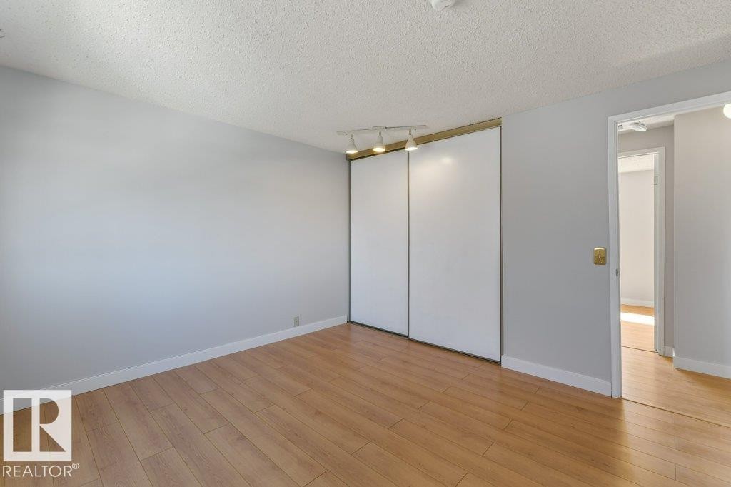 Room featuring wood-finish flooring, light gray walls, white baseboards, and a textured ceiling - 3736 12 Avenue, Edmonton, AB - Indoor Photo Showing Other Room