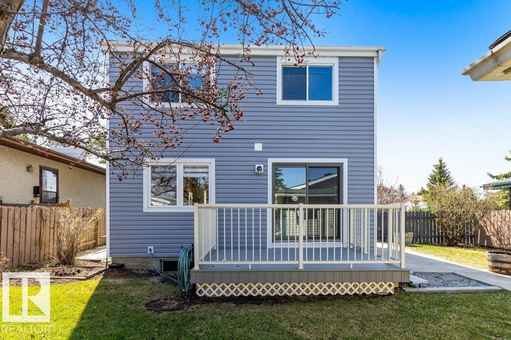 Rear exterior featuring horizontal siding, a ground-level deck with white railings, and sliding glass door access - 3736 12 Avenue, Edmonton, AB - Outdoor With Deck Patio Veranda