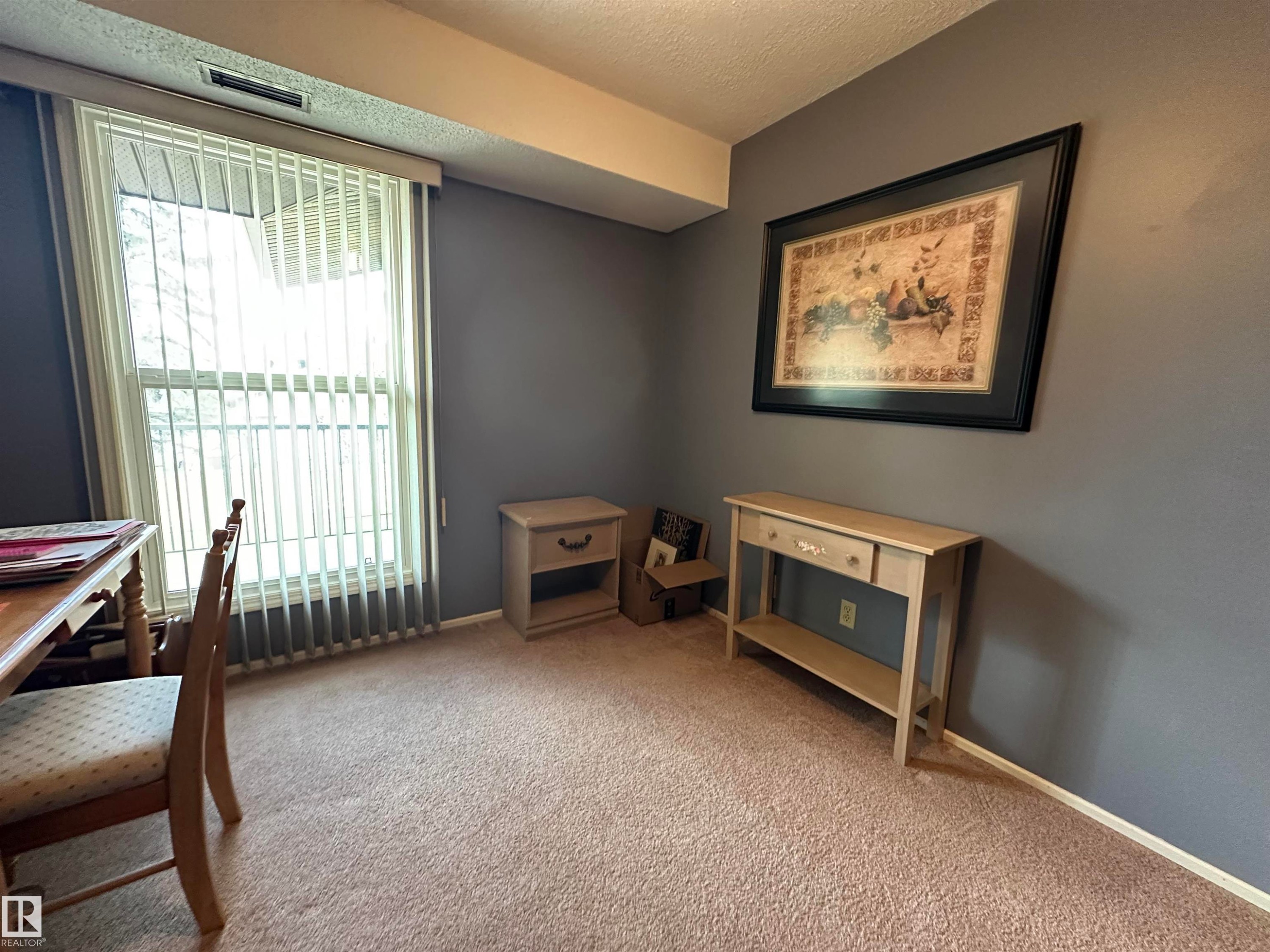 Carpeted room featuring a large window with vertical blinds, painted walls, and a ceiling-mounted air vent - 2071 Saddleback Road, Edmonton, AB - Indoor