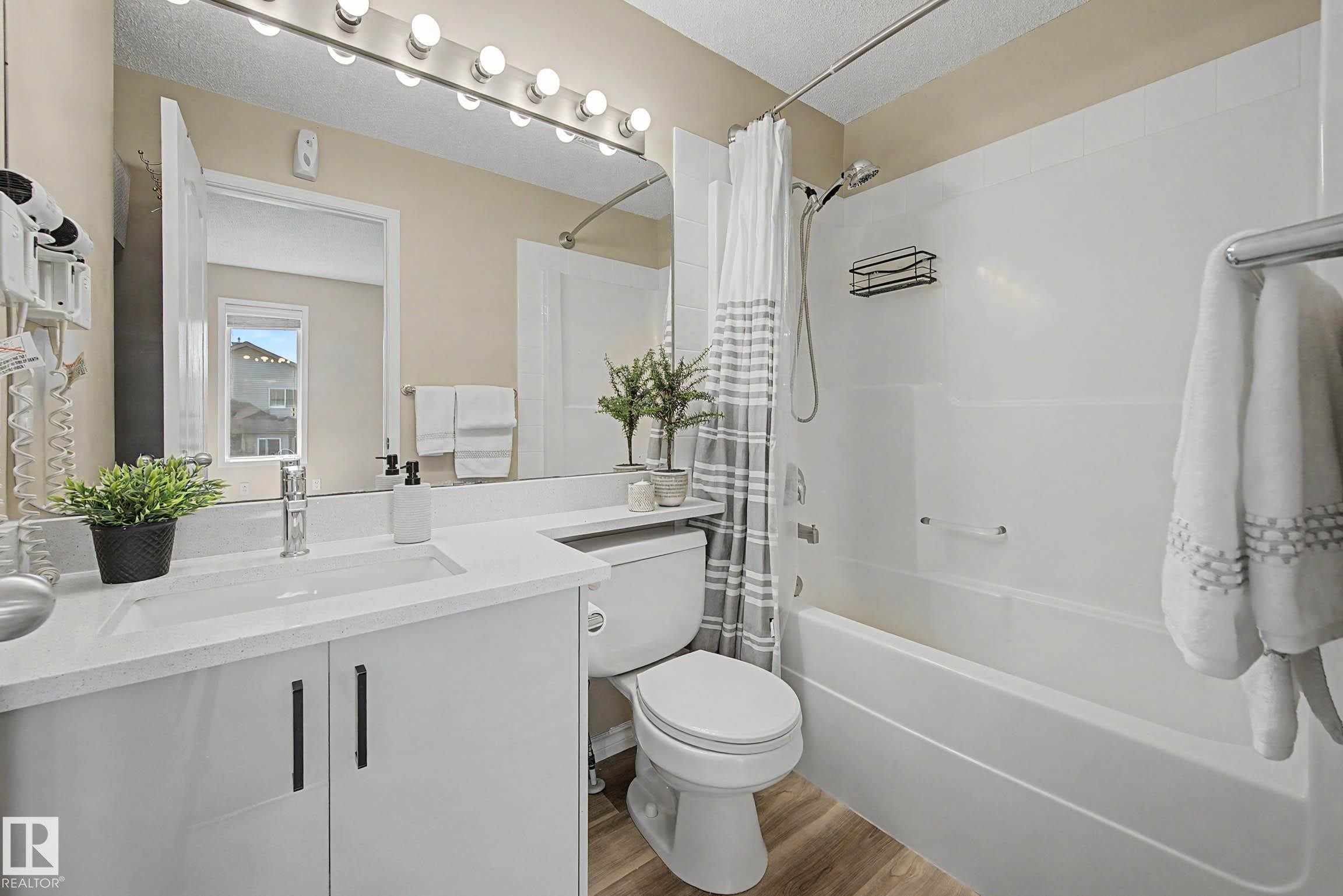 Bathroom featuring a white vanity with an integrated sink, light-colored countertop, and matte black hardware - 7723 7A Avenue, Edmonton, AB - Indoor Photo Showing Bathroom