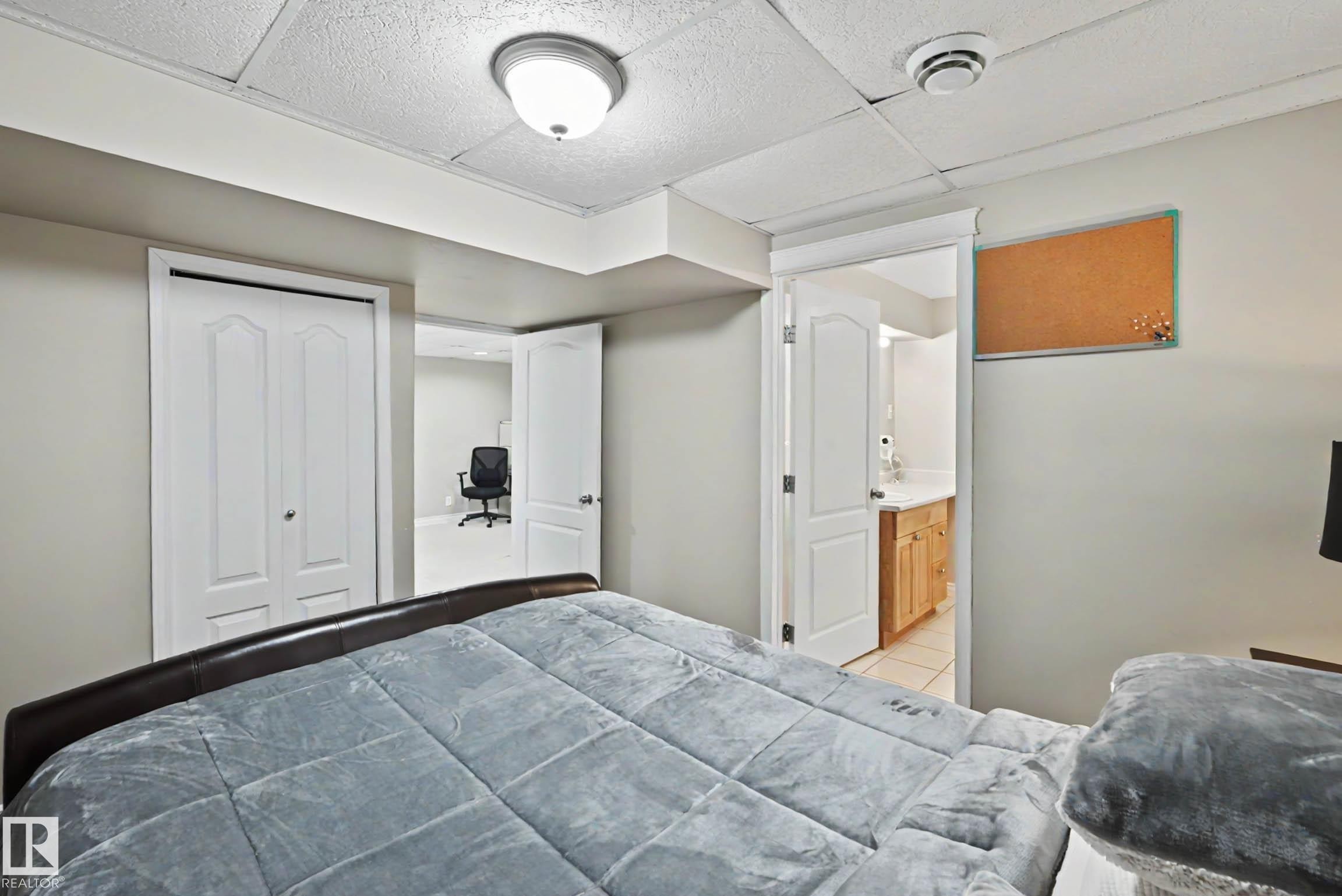 Bedroom featuring neutral wall paint, recessed lighting, white bi-fold closet doors, and access to an additional room and a bathroom with wood-finish cabinetry - 7723 7A Avenue, Edmonton, AB - Indoor Photo Showing Bedroom
