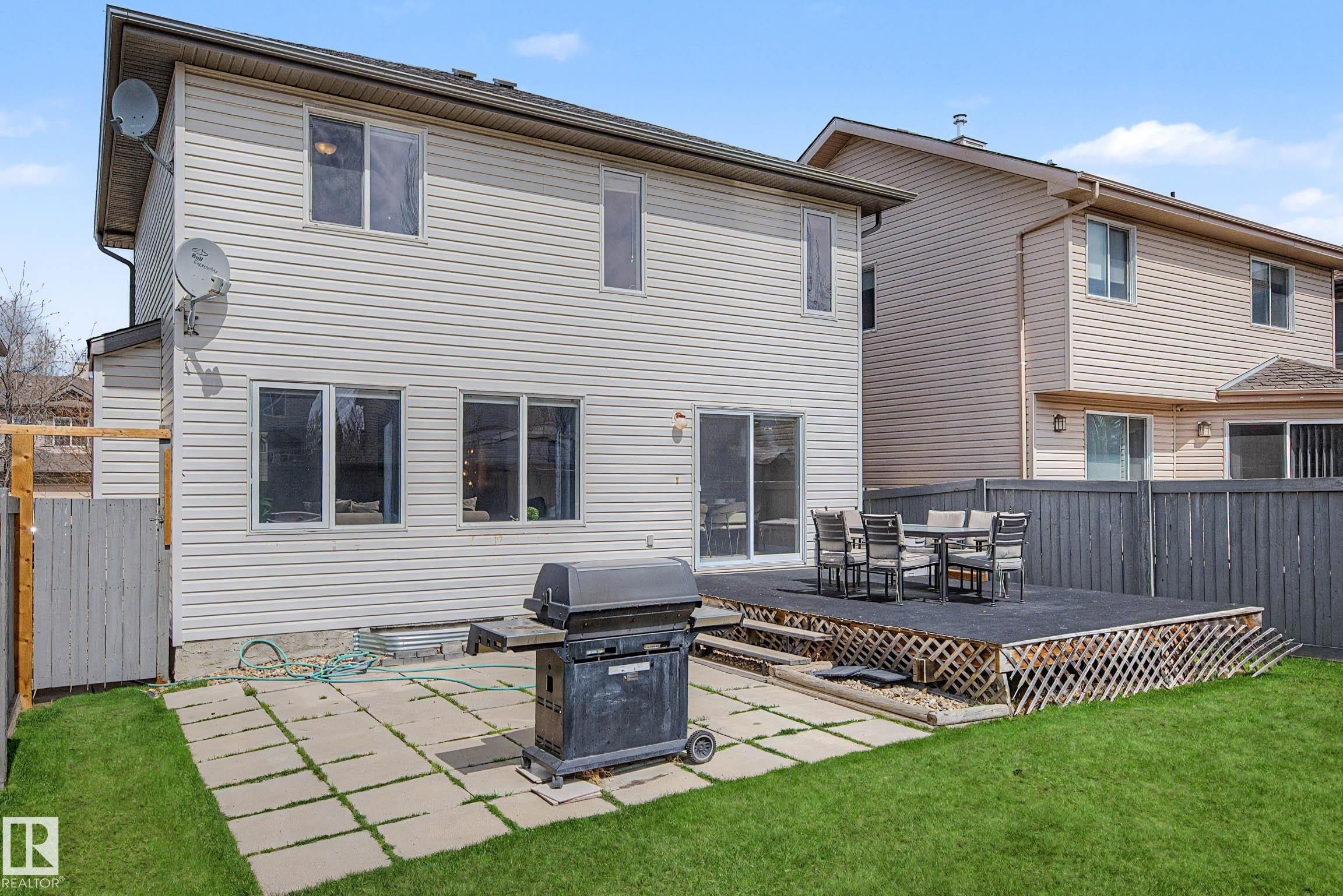 Expansive backyard featuring a manicured lawn, a large raised deck, a patio with square pavers, and a privacy fence - 7723 7A Avenue, Edmonton, AB - Outdoor With Deck Patio Veranda With Exterior