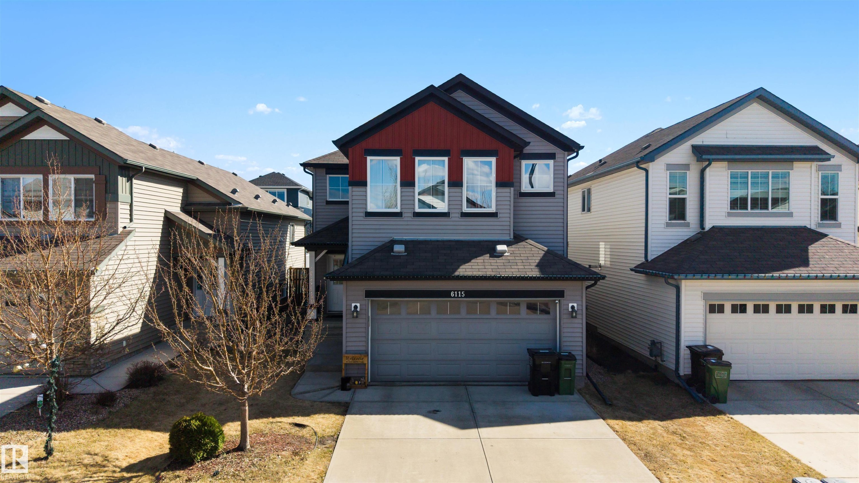 Contemporary two-story residence featuring a two-car garage with overhead door, a concrete driveway, and siding exterior with red and dark gray accents - 6115 18 Avenue, Edmonton, AB - Outdoor With Facade