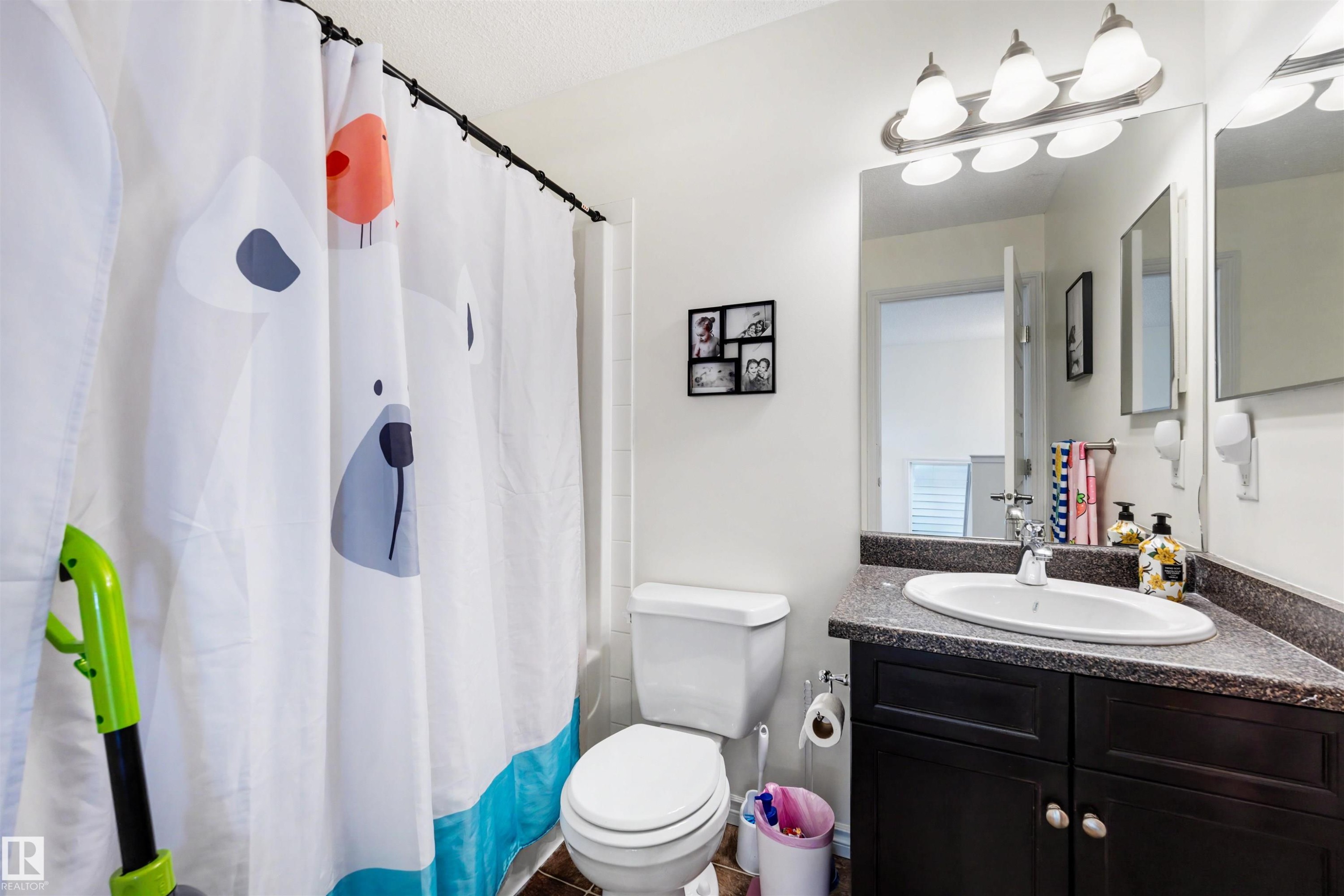 Bathroom featuring a dark wood-finish vanity with a speckled countertop and an undermount sink - 6115 18 Avenue, Edmonton, AB - Indoor Photo Showing Bathroom