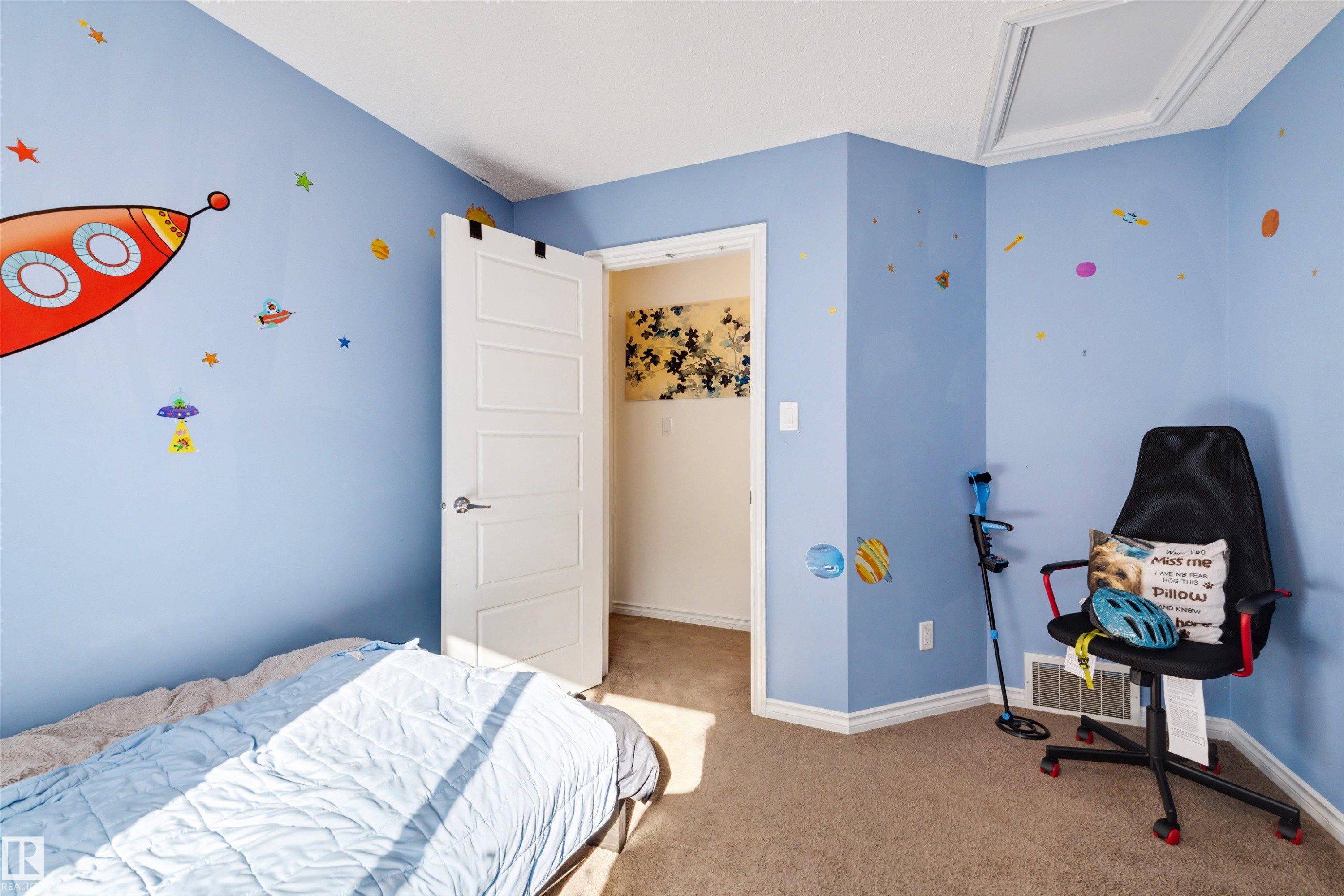Room featuring light blue walls with decorative decals, a white paneled door with brushed nickel hardware, and neutral carpet flooring - 6115 18 Avenue, Edmonton, AB - Indoor Photo Showing Bedroom