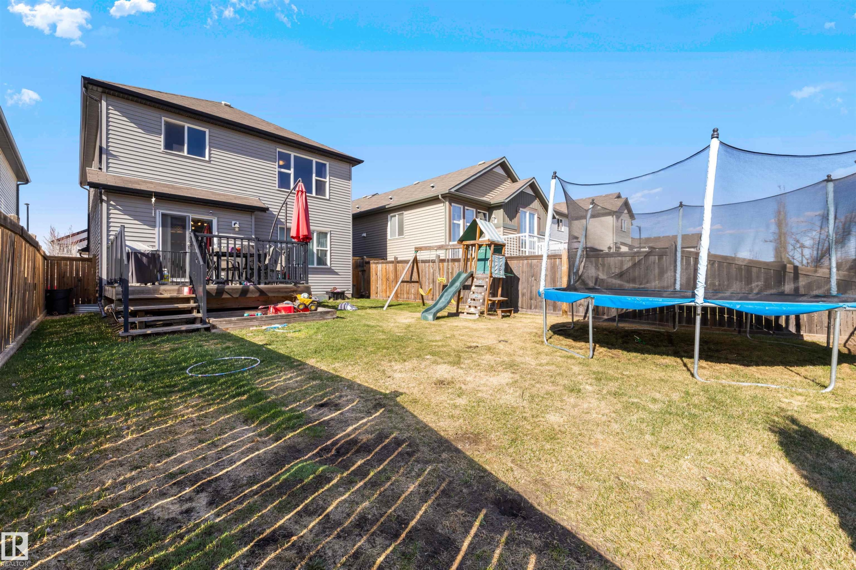 Expansive backyard featuring a wood deck with railings, a sliding glass door entry, and gray vinyl siding - 6115 18 Avenue, Edmonton, AB - Outdoor With Deck Patio Veranda