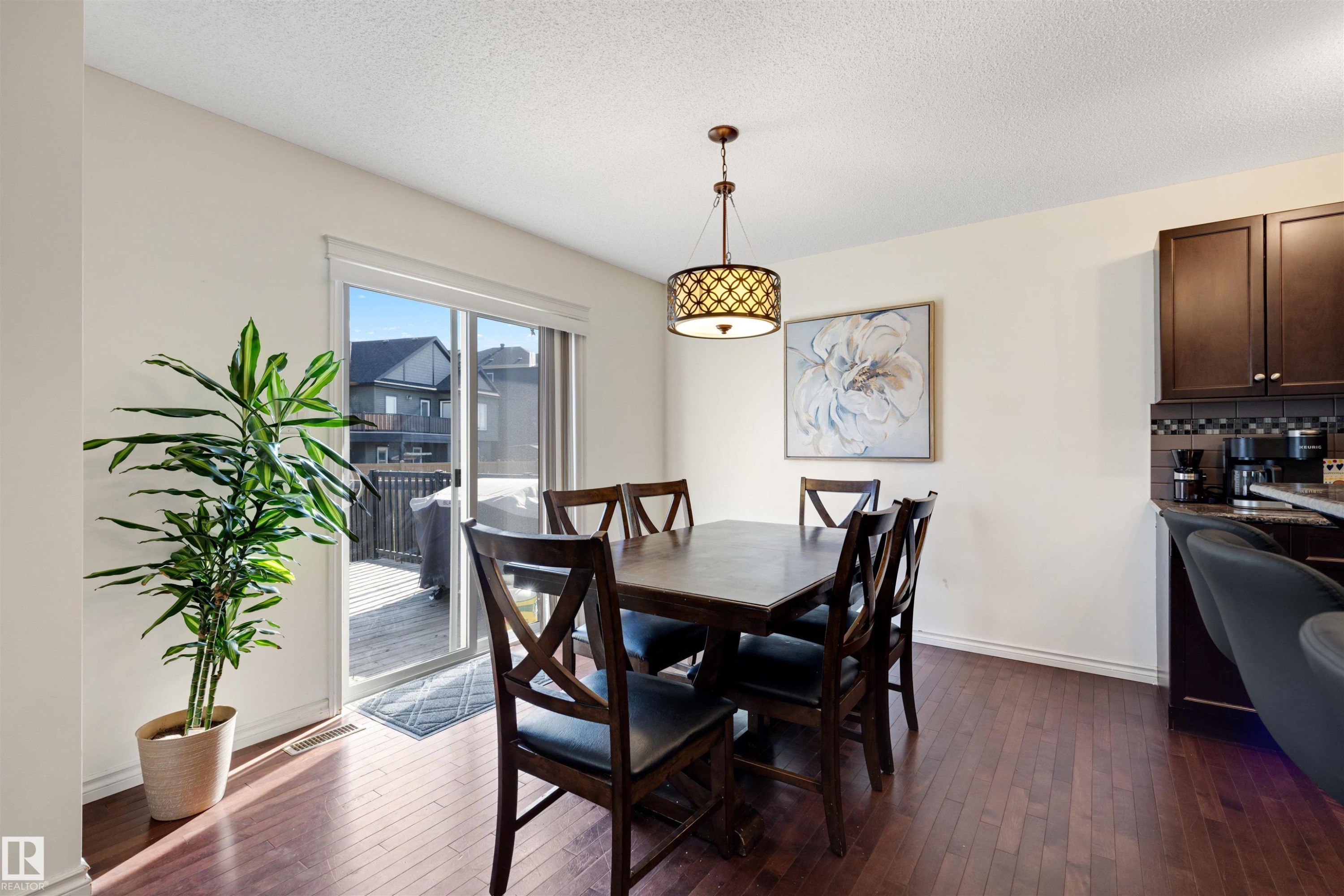 Dining area featuring rich wood-finish flooring, a contemporary chandelier, and sliding glass doors opening to a deck - 6115 18 Avenue, Edmonton, AB - Indoor Photo Showing Dining Room
