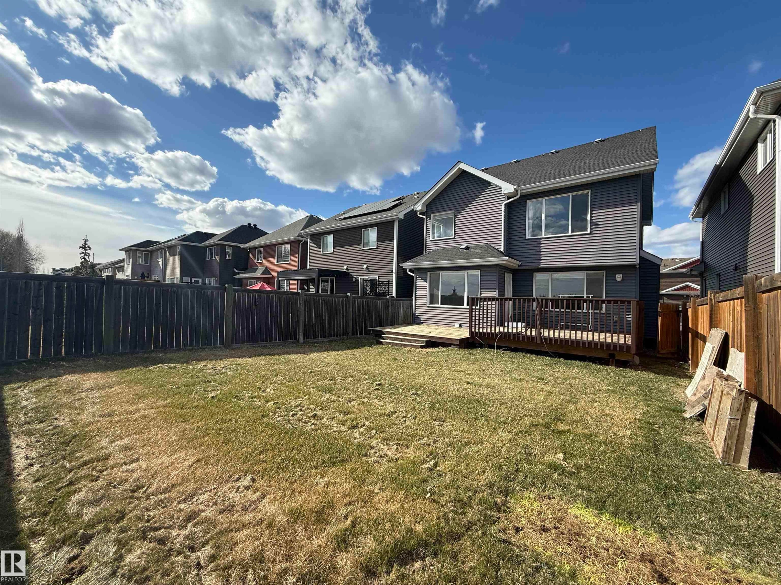 Private fenced backyard featuring a spacious wooden deck with direct access to the interior, complemented by large windows and siding exterior - 16627 18 Avenue, Edmonton, AB - Outdoor